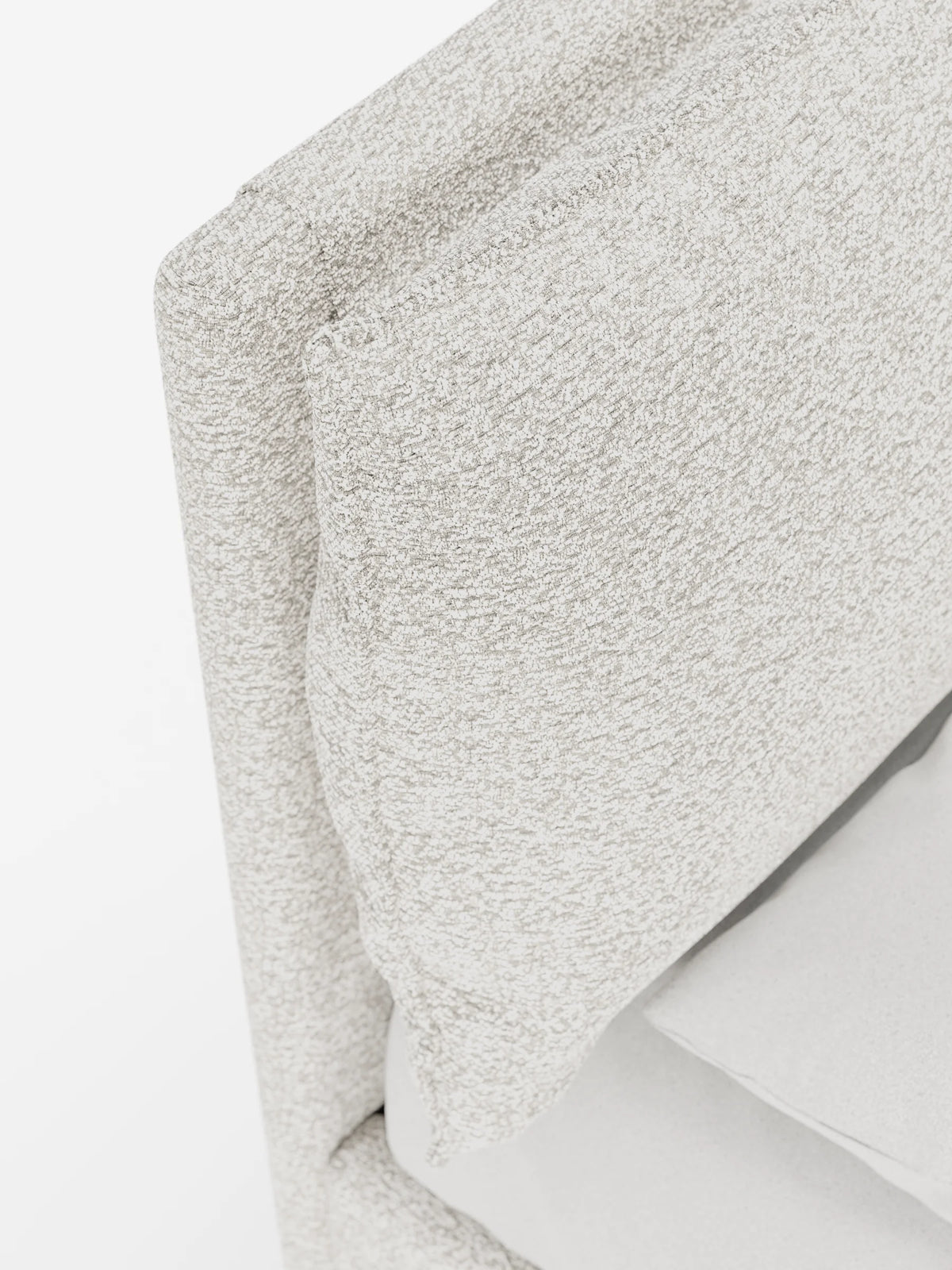 Un primo piano del letto imbottito ZAYRON con contenitore e morbidi cuscini regolabili, caratterizzato da cuscini spessi e regolabili in tessuto beige chiaro screziato con trama a rilievo su sfondo bianco.