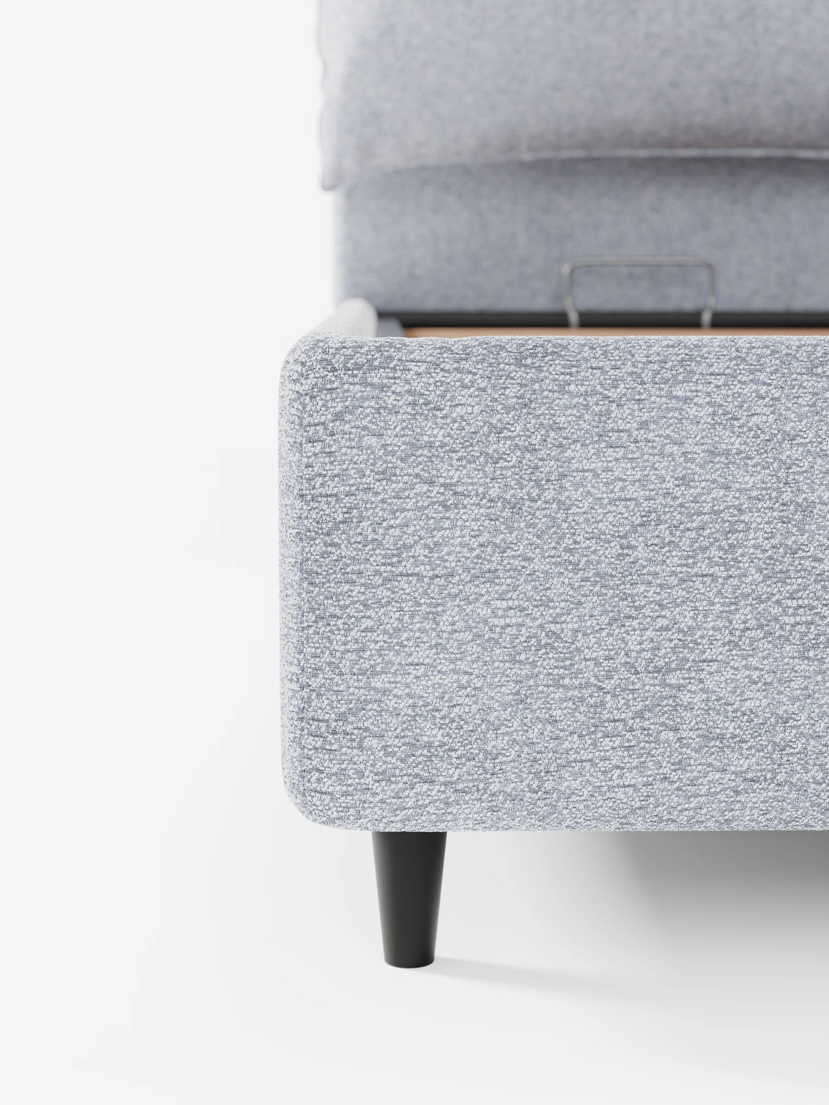 Un primo piano di un letto ZAYRON azzurro, imbottito, con contenitore e morbidi cuscini regolabili, caratterizzato da un design moderno con una gamba affusolata scura su sfondo bianco.