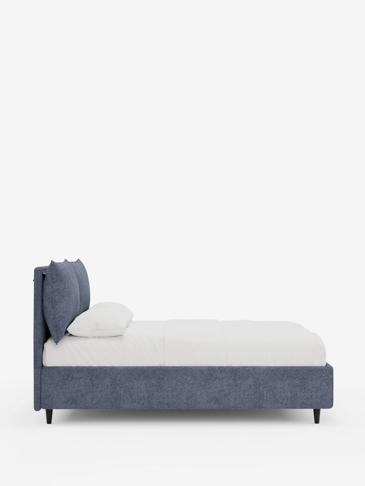 Vista laterale di un letto imbottito ZAYRON con contenitore e morbidi cuscini regolabili in tessuto blu, caratterizzato da due grandi cuscini, biancheria da letto bianca e piedini corti scuri su uno sfondo bianco a tinta unita.