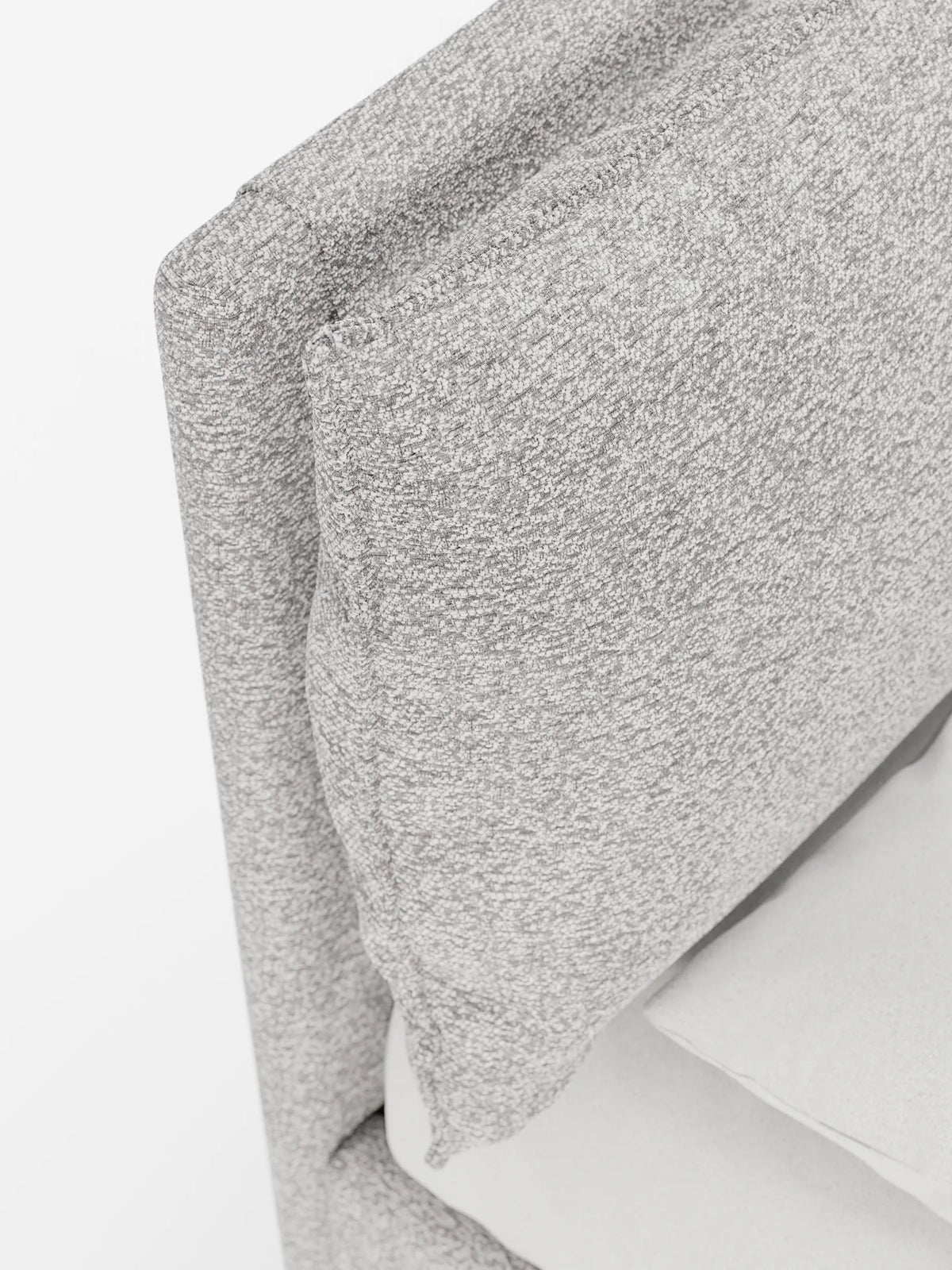 Un primo piano di un letto imbottito ZAYRON con contenitore e morbidi cuscini regolabili, caratterizzato da due schienali regolabili in tessuto grigio chiaro con texture maculata su sfondo bianco.