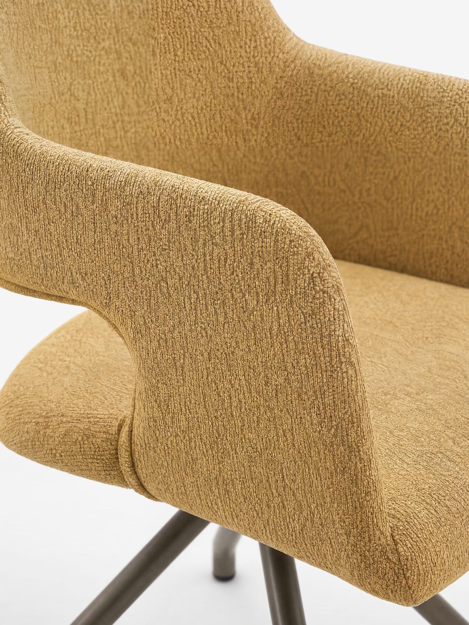 Primo piano della sedia imbottita di design Zefira di Divani.Store, caratterizzata da braccioli ricurvi, tessuto giallo senape effetto cotone e gambe in metallo con finitura champagne, su uno sfondo bianco a tinta unita.