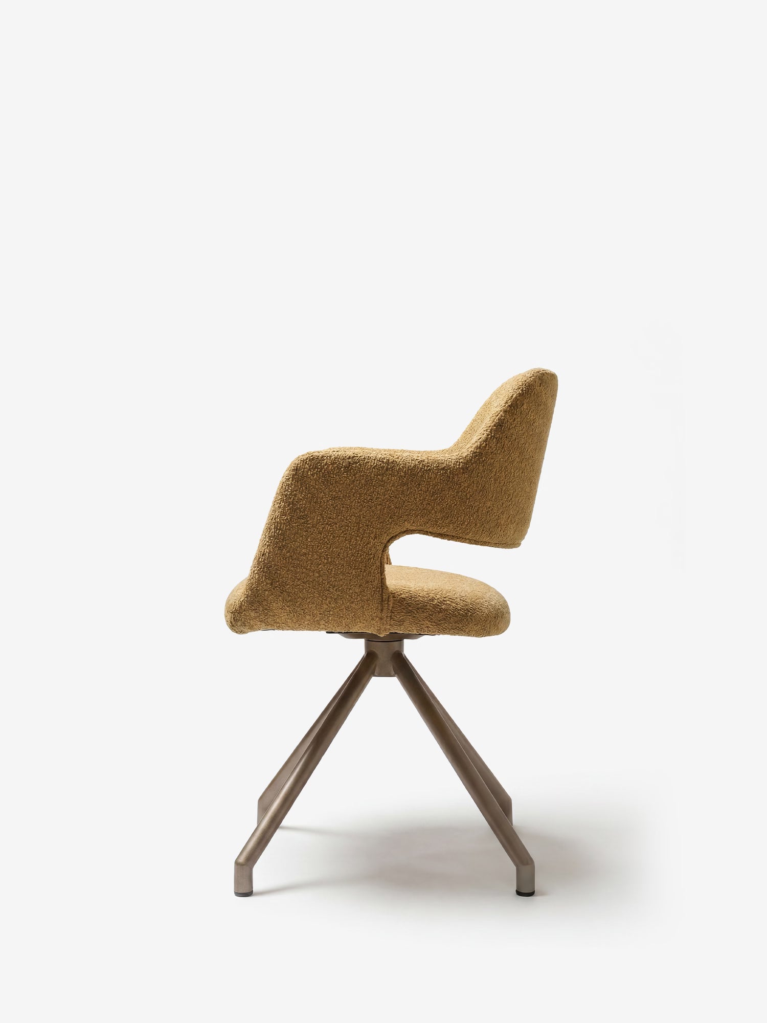 La sedia imbottita di design Zefira di Divani.Store è realizzata in tessuto effetto cotone color senape, presenta uno schienale curvo con apertura, braccioli e una base a quattro gambe in metallo color champagne, ed è raffigurata su uno sfondo bianco a tinta unita.