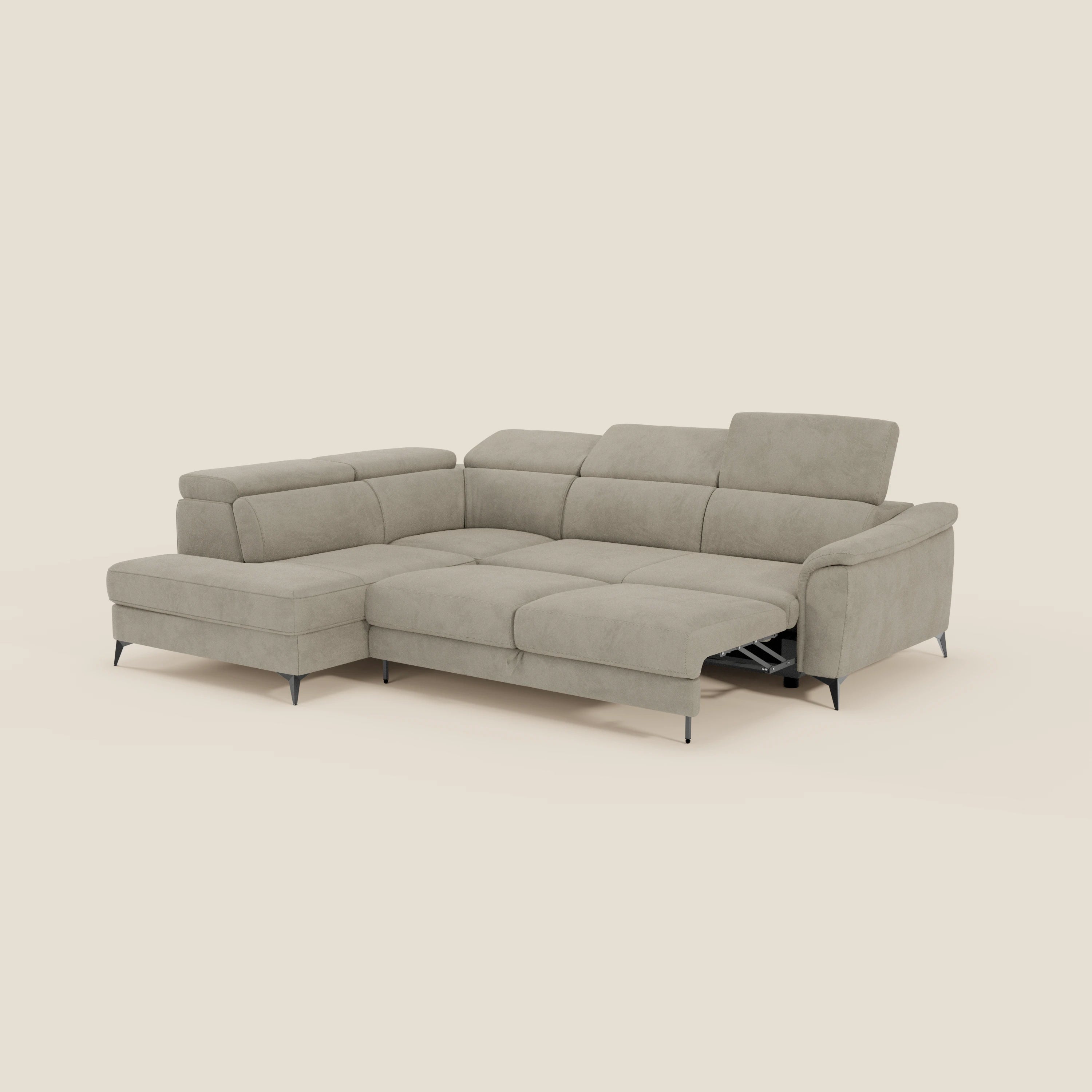 L'Arcos Divano angolare di Divani.Store, in microfibra impermeabile T11 taupe, è caratterizzato da alte gambe nere e poggiatesta reclinabili. Una seduta offre un meccanismo relax elettrico con poggiapiedi esteso su uno sfondo beige chiaro.