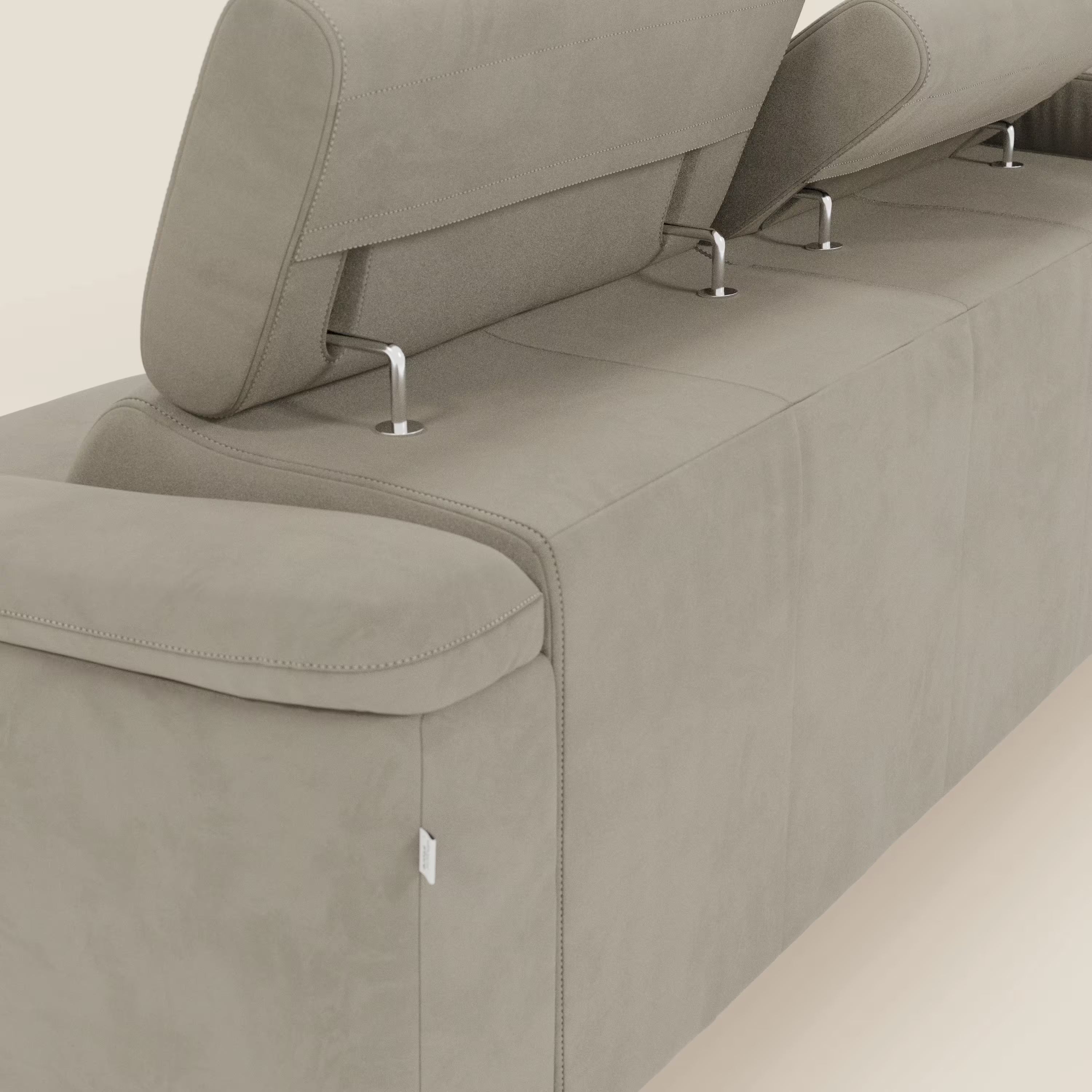 L'Arcos Divano con penisola di Divani.Store è caratterizzato da gambe alte, poggiatesta regolabili con supporti metallici e ampi braccioli imbottiti in microfibra tortora impermeabile T11, che mettono in mostra l'artigianalità italiana su uno sfondo bianco sporco.