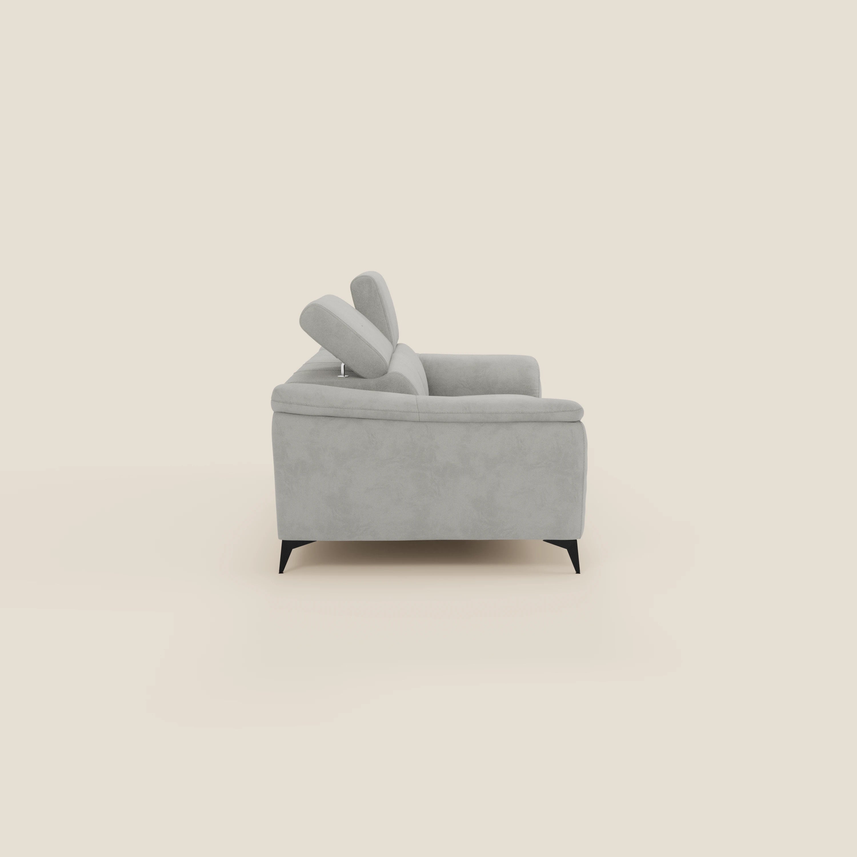 Arcos Divano 3 posti di Divani.Store in microfibra impermeabile grigio chiaro T11 è caratterizzato da alte gambe nere e da due poggiatesta regolabili, visti di lato su uno sfondo crema, che ne evidenziano lo stile da moderna chaise longue.