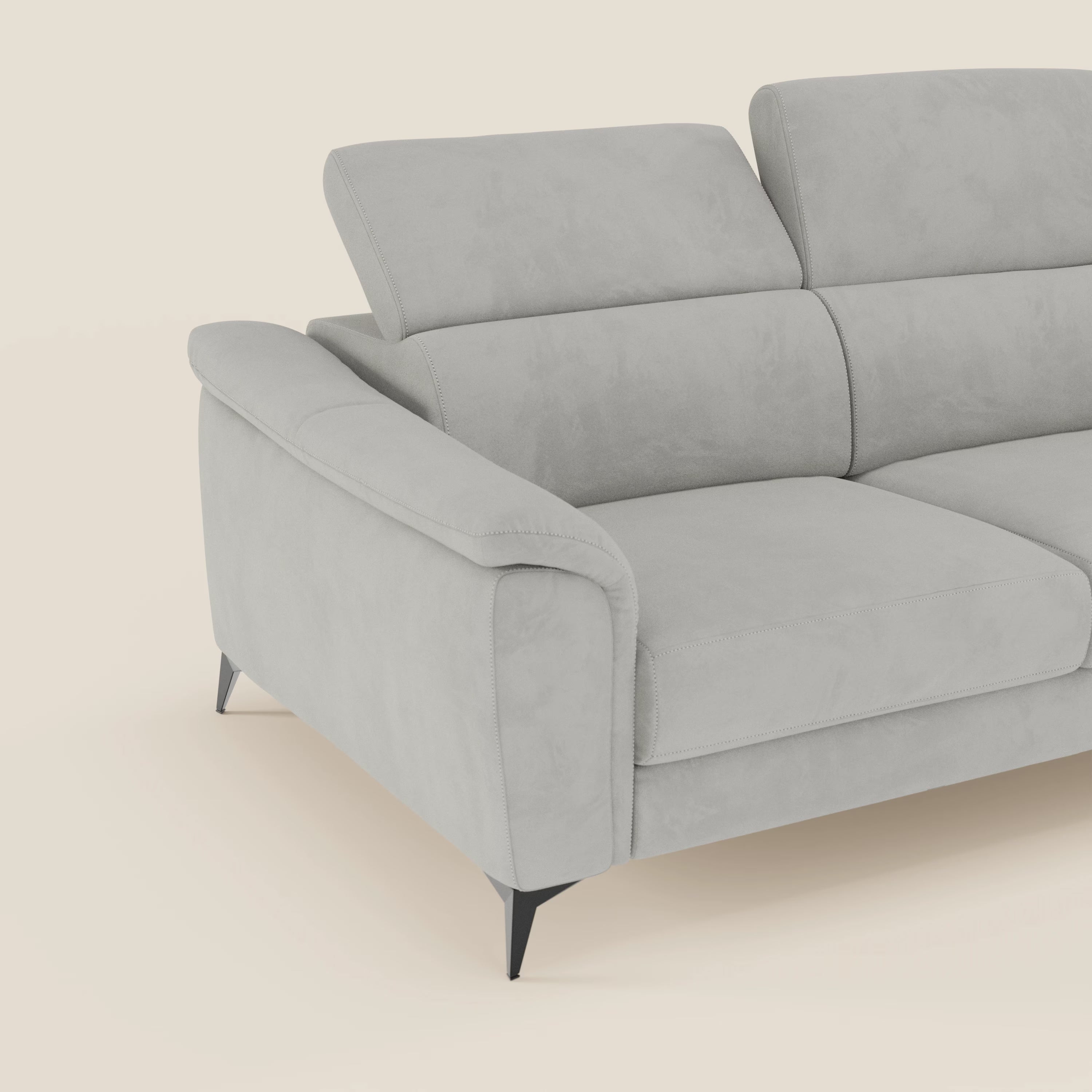 Arcos Divano 3 posti di Divani.Store è caratterizzato da microfibra T11 impermeabile grigio chiaro, gambe alte e poggiatesta reclinabili. Solo una parte di questo divano moderno con ampi braccioli è mostrata su uno sfondo bianco sporco.