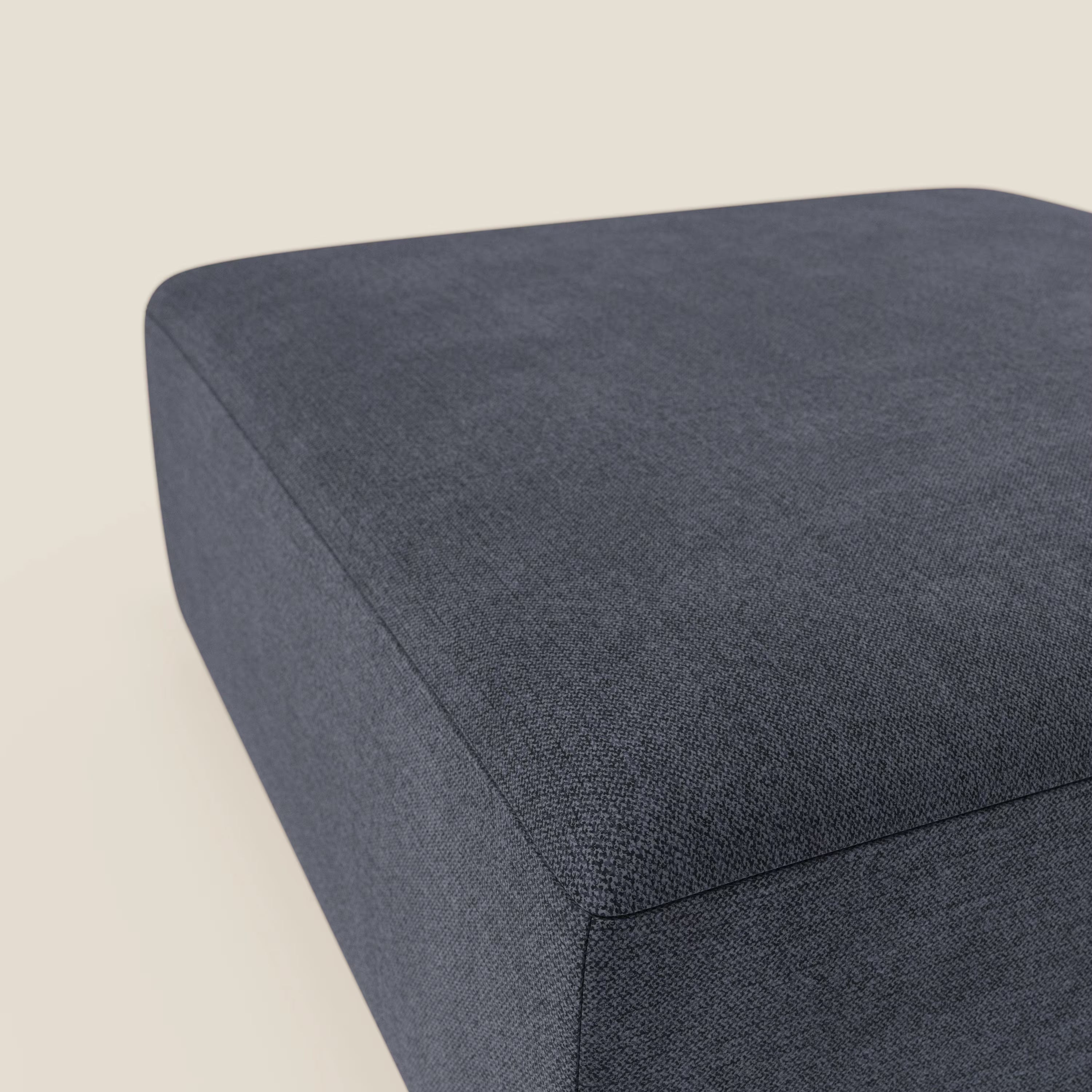 Primo piano del pouf BonBon di Divani.Store in tessuto smacchiabile T23 blu ardesia, caratterizzato da bordi netti e finitura strutturata, su uno sfondo neutro. L'immagine evidenzia il suo design modulare moderno e minimalista.