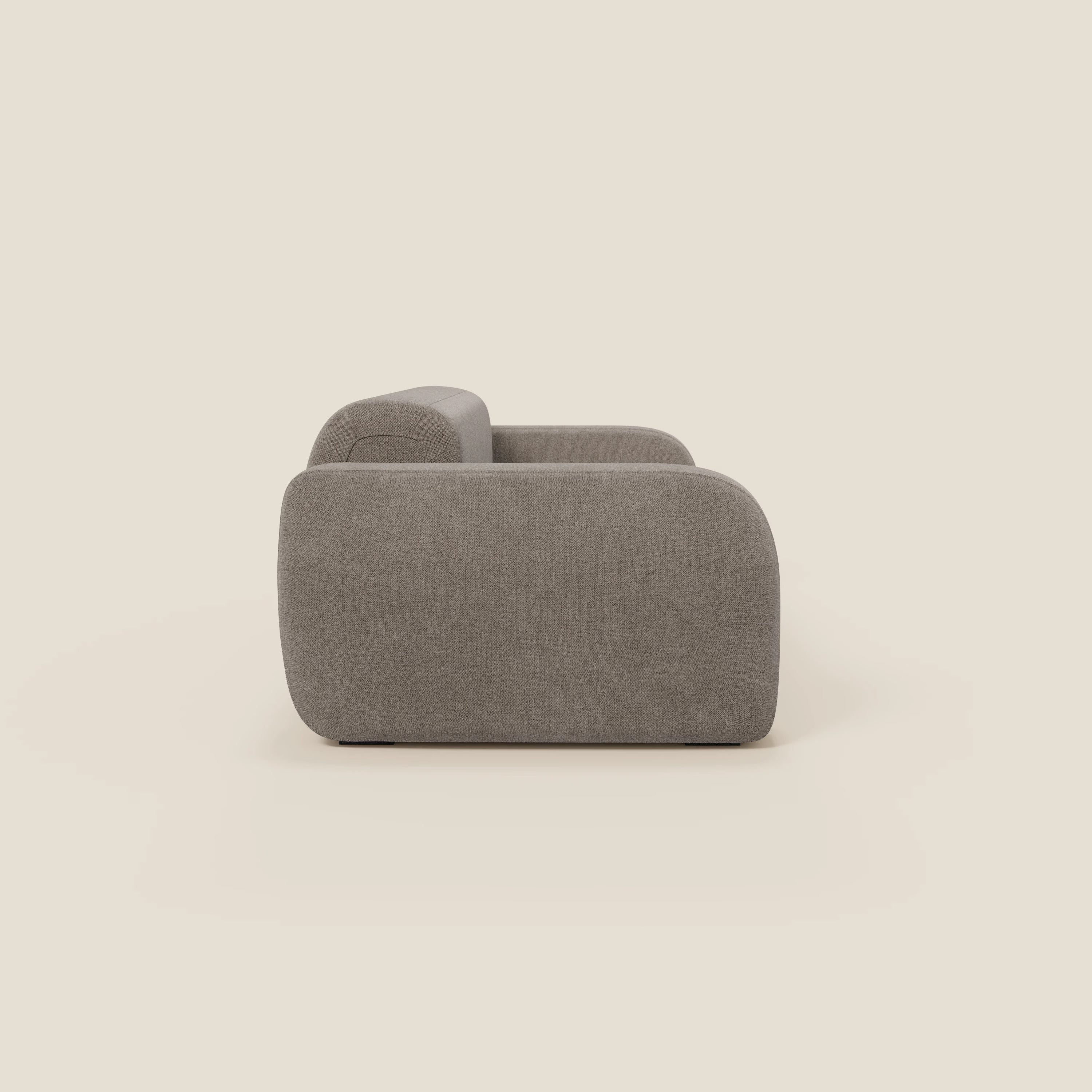 Il BonBon Divano modulare Lineare 220 di Divani.Store è presentato lateralmente su uno sfondo beige chiaro, con linee arrotondate e minimaliste, braccioli spessi e rivestimento in talpa smacchiabile T23.