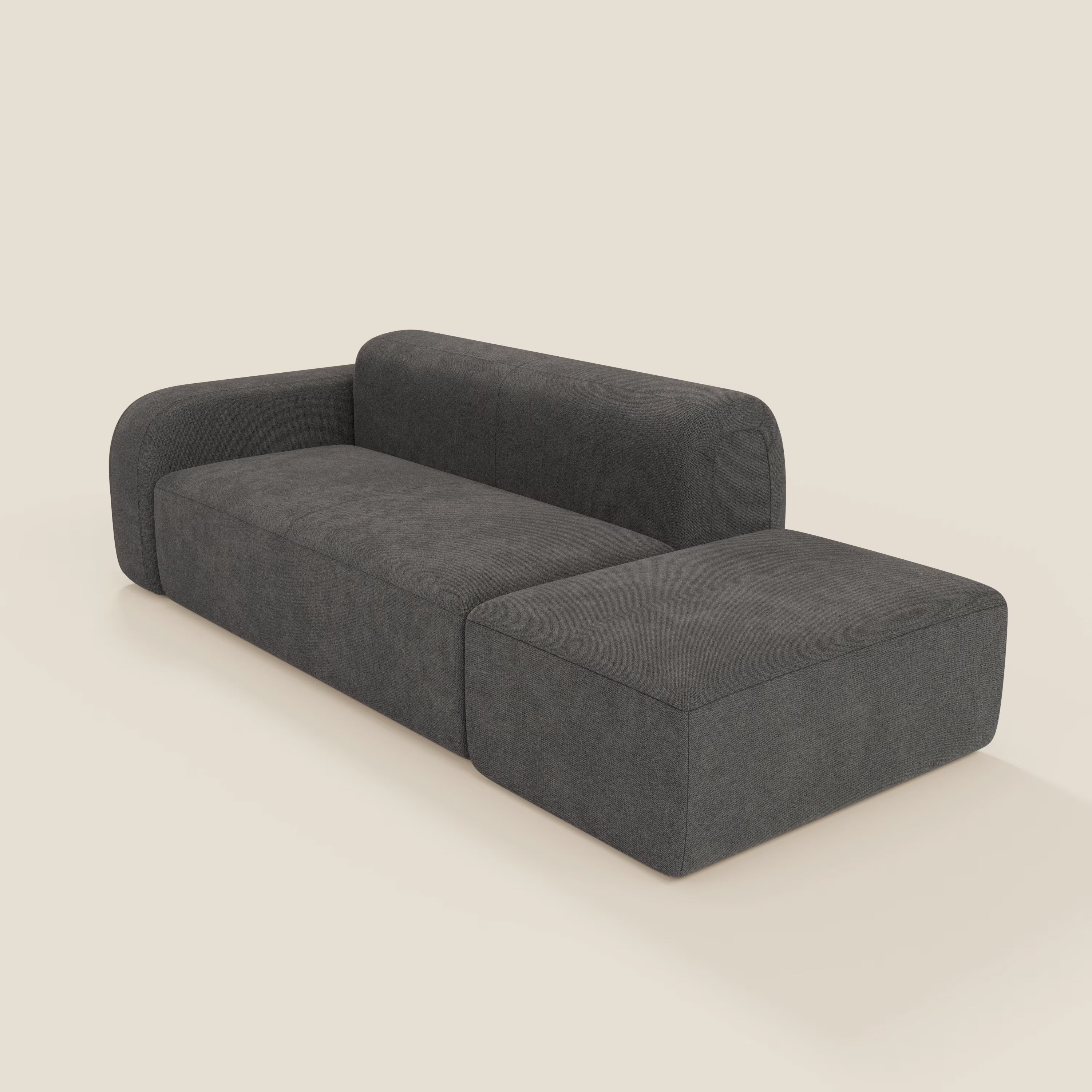 Il divano modulare componibile BonBon di Divani.Store, in tessuto smacchiabile T23 antracite, presenta un design elegante a forma di L con cuscini bassi e squadrati, bracciolo spesso e arrotondato su un'estremità e assenza di gambe a vista per un look moderno.