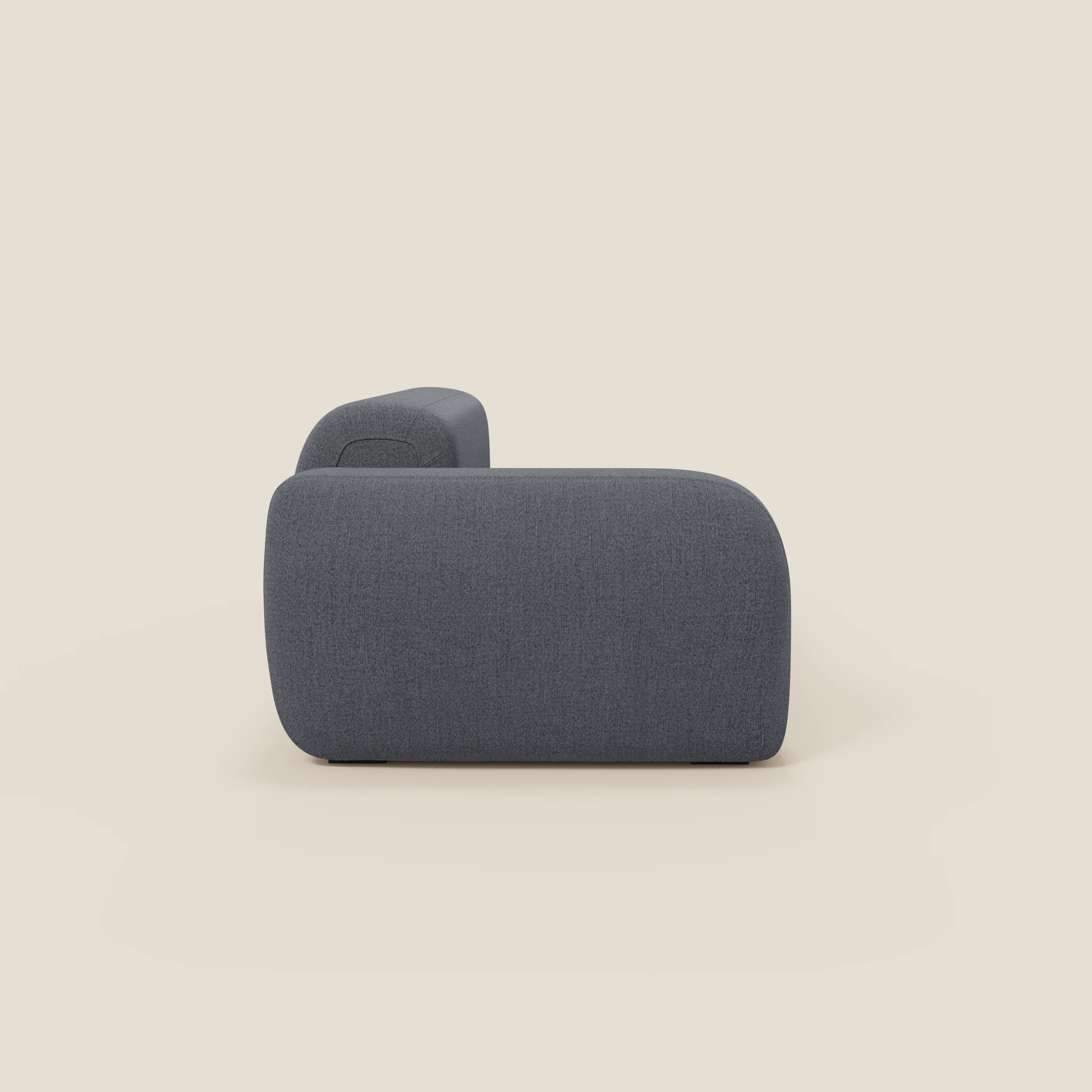 Il divano componibile BonBon di Divani.Store è presentato lateralmente in tessuto smacchiabile T23 blu grafite, con pouf terminale, bordi arrotondati e lisci, profilo basso e squadrato e un look morbido e contemporaneo su uno sfondo beige chiaro.