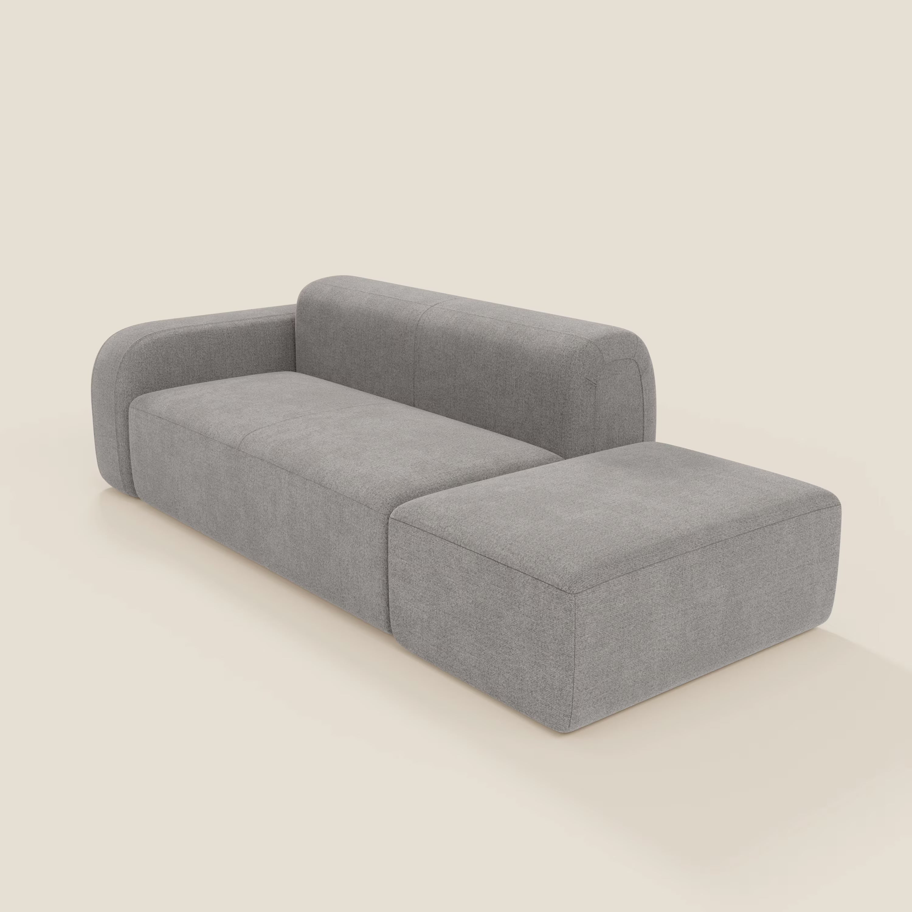 Il BonBon Divano componibile di Divani.Store è caratterizzato da un tessuto smacchiabile T23 grigio, da un bracciolo sinistro e da una chaise con pouf terminale destro per una moderna composizione a L, su sfondo neutro.