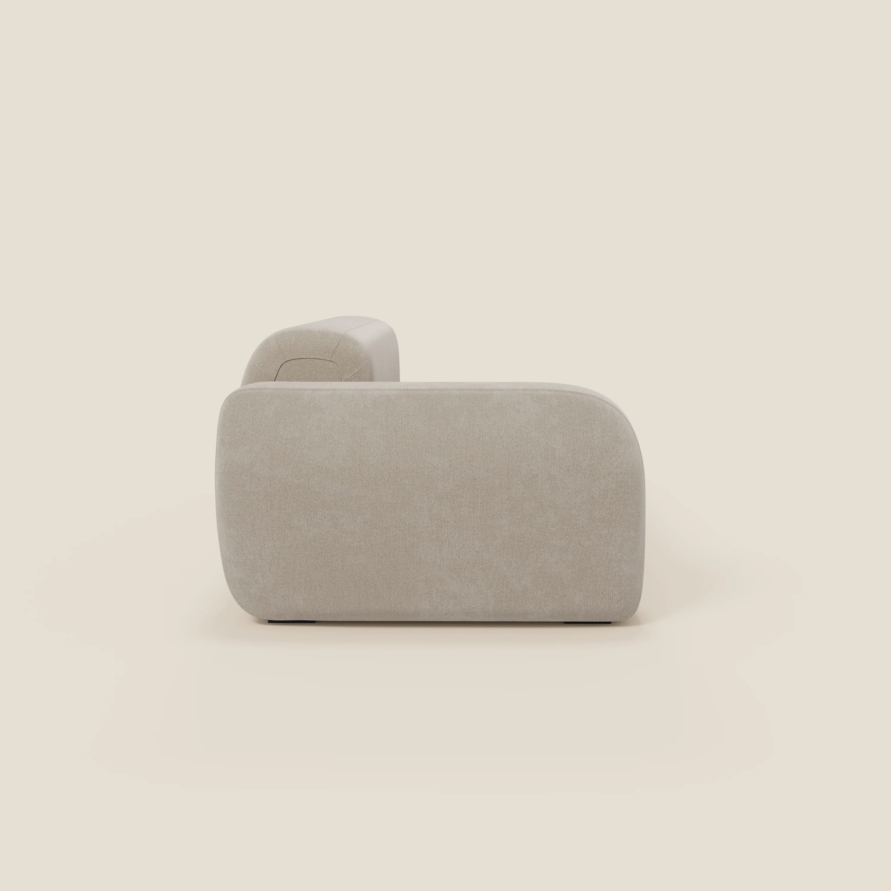 Vista laterale del divano componibile BonBon Divano di Divani.Store in tessuto smacchiabile T23 panna, caratterizzato da schienale e braccioli arrotondati, bordi curvi minimalisti e assenza di gambe visibili su uno sfondo bianco sporco.