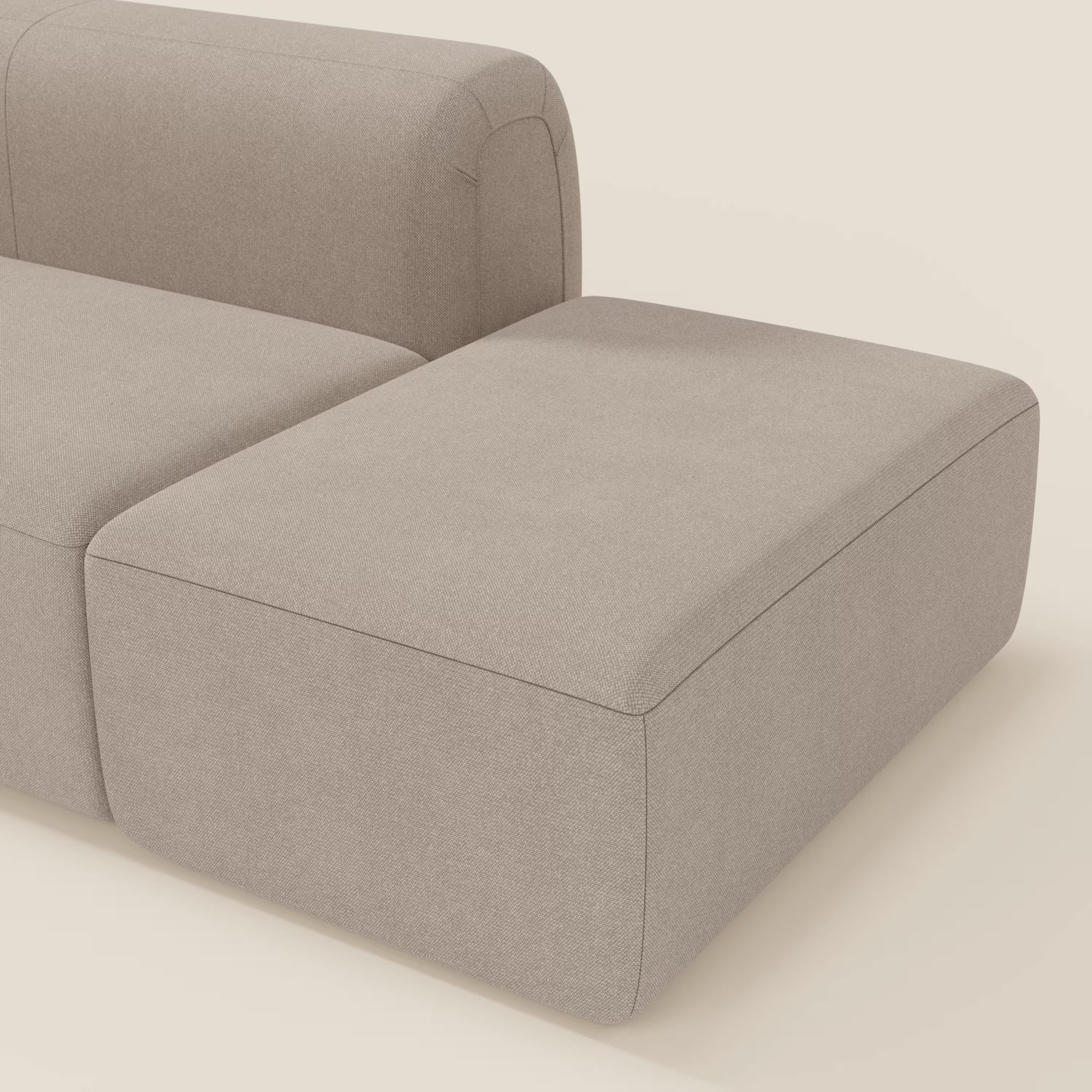 Il BonBon Divano componibile di Divani.Store è caratterizzato da uno smacchiabile tessuto tortora T23 e da un pouf terminale, che offre un look moderno e minimalista con linee pulite e bordi arrotondati su uno sfondo chiaro.