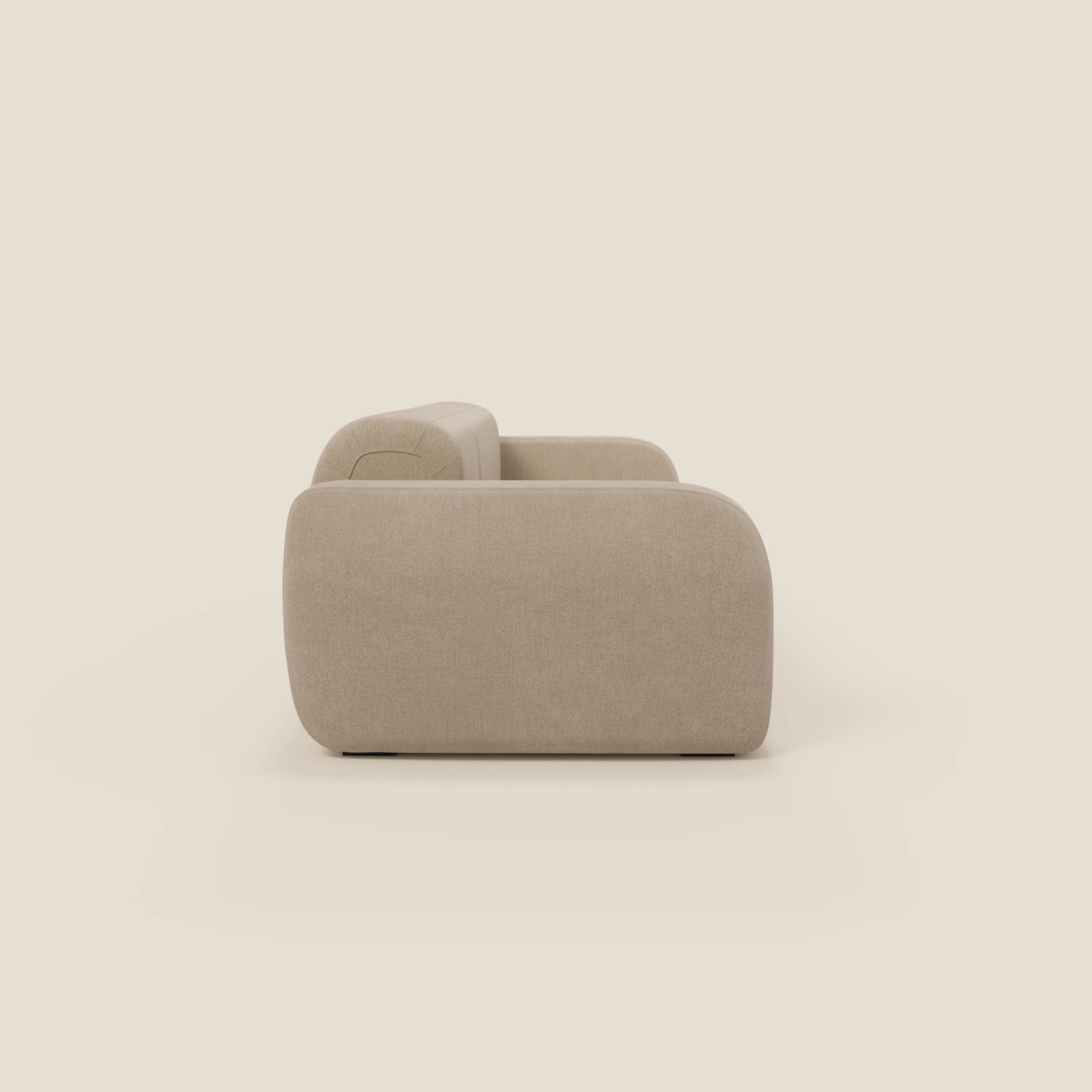 Il BonBon Divano componibile - Composizione Spaccamattone in tessuto smacchiabile T23 beige di Divani.Store è esposto lateralmente su uno sfondo crema chiaro, con braccioli spessi e bordi lisci e arrotondati per un look morbido e minimalista.