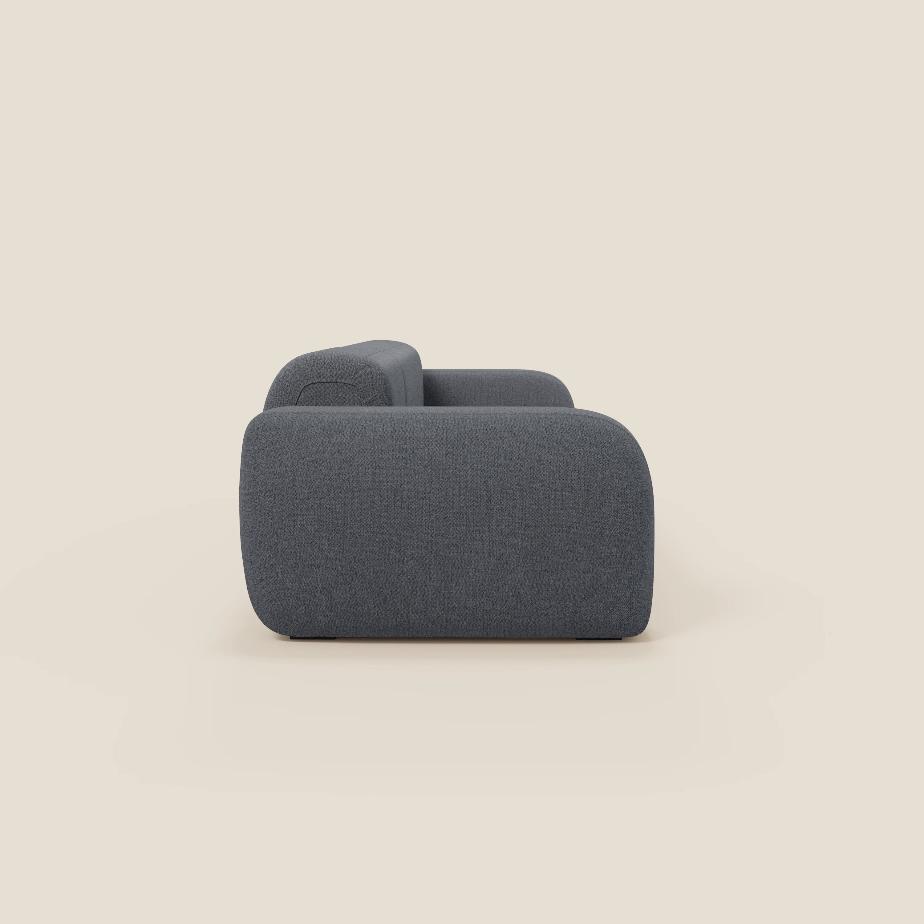Il BonBon Divano componibile di Divani.Store in grafite T23 blu è presentato lateralmente su uno sfondo beige chiaro, con un design moderno e minimalista, con bordi arrotondati e profilo basso.