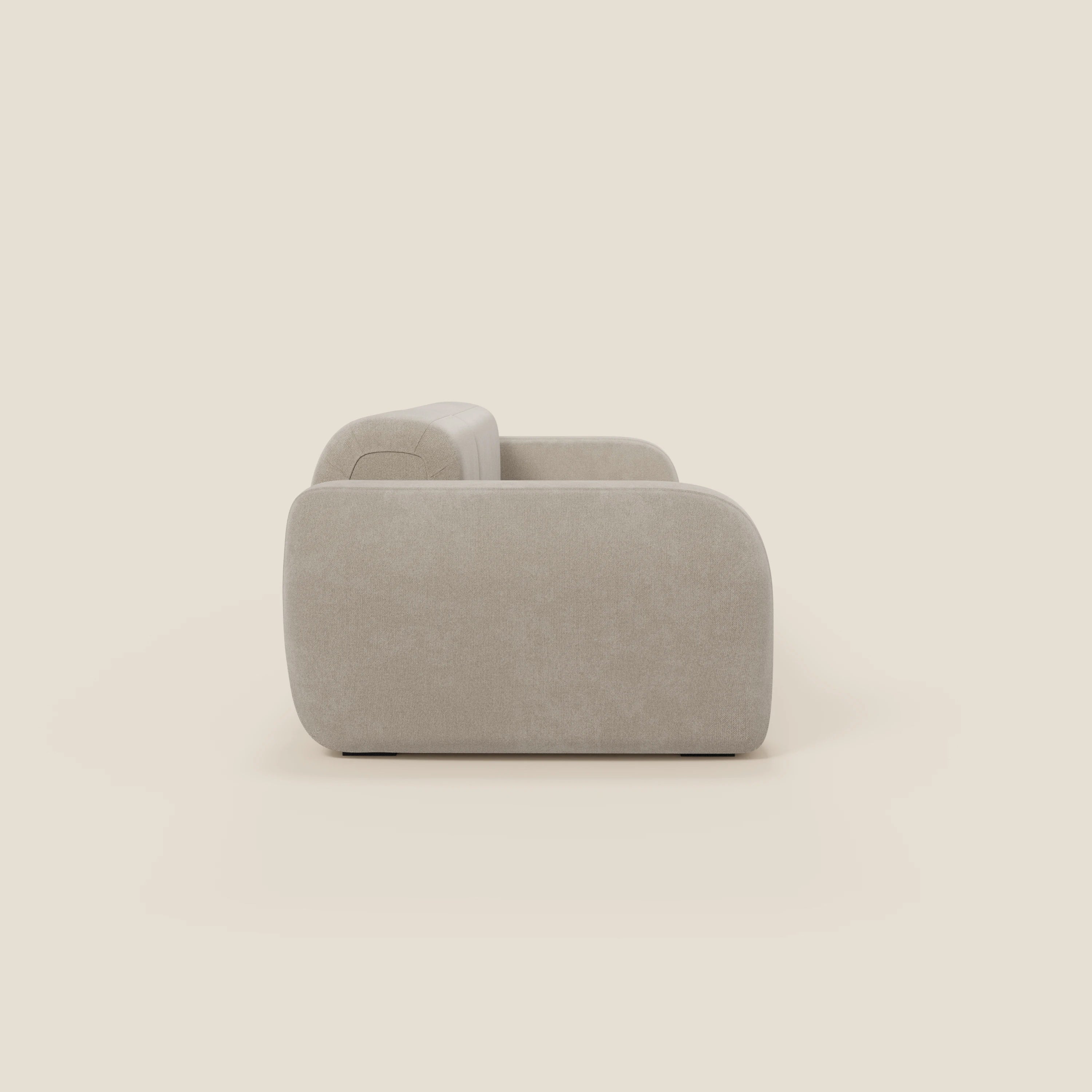Vista laterale del BonBon Divano componibile - Composizione Spaccamattone di Divani.Store in smacchiabile panna T23, caratterizzato da bracciolo e schienale con imbottitura arrotondata, rivestimento vellutato e design unico in un ambiente minimalista.