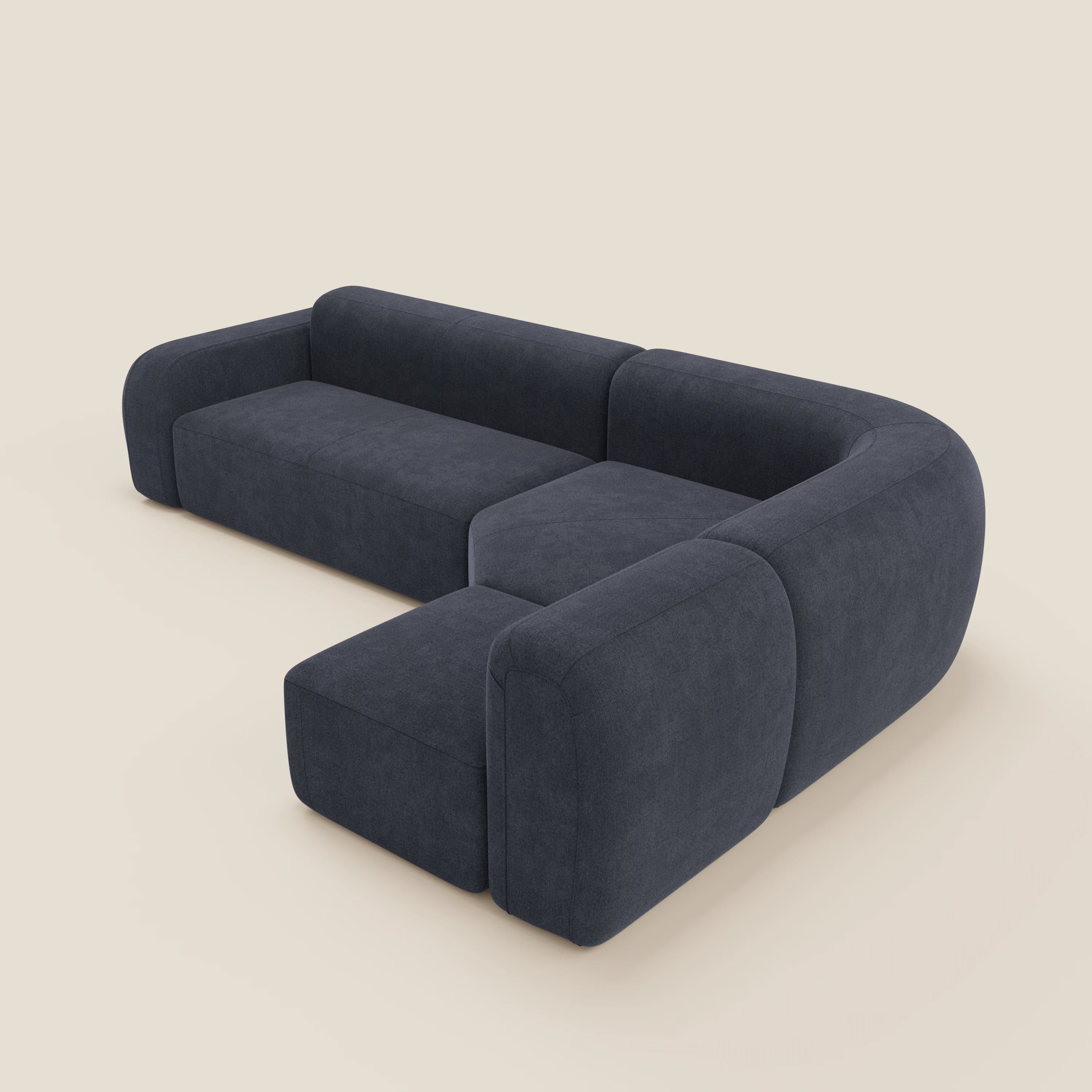 Il divano angolare componibile e modulare BonBon di Divani.Store, in tessuto antimacchia T23 ardesia blu, è caratterizzato da bordi arrotondati e da uno schienale basso a L con pouf abbinato, su sfondo panna.