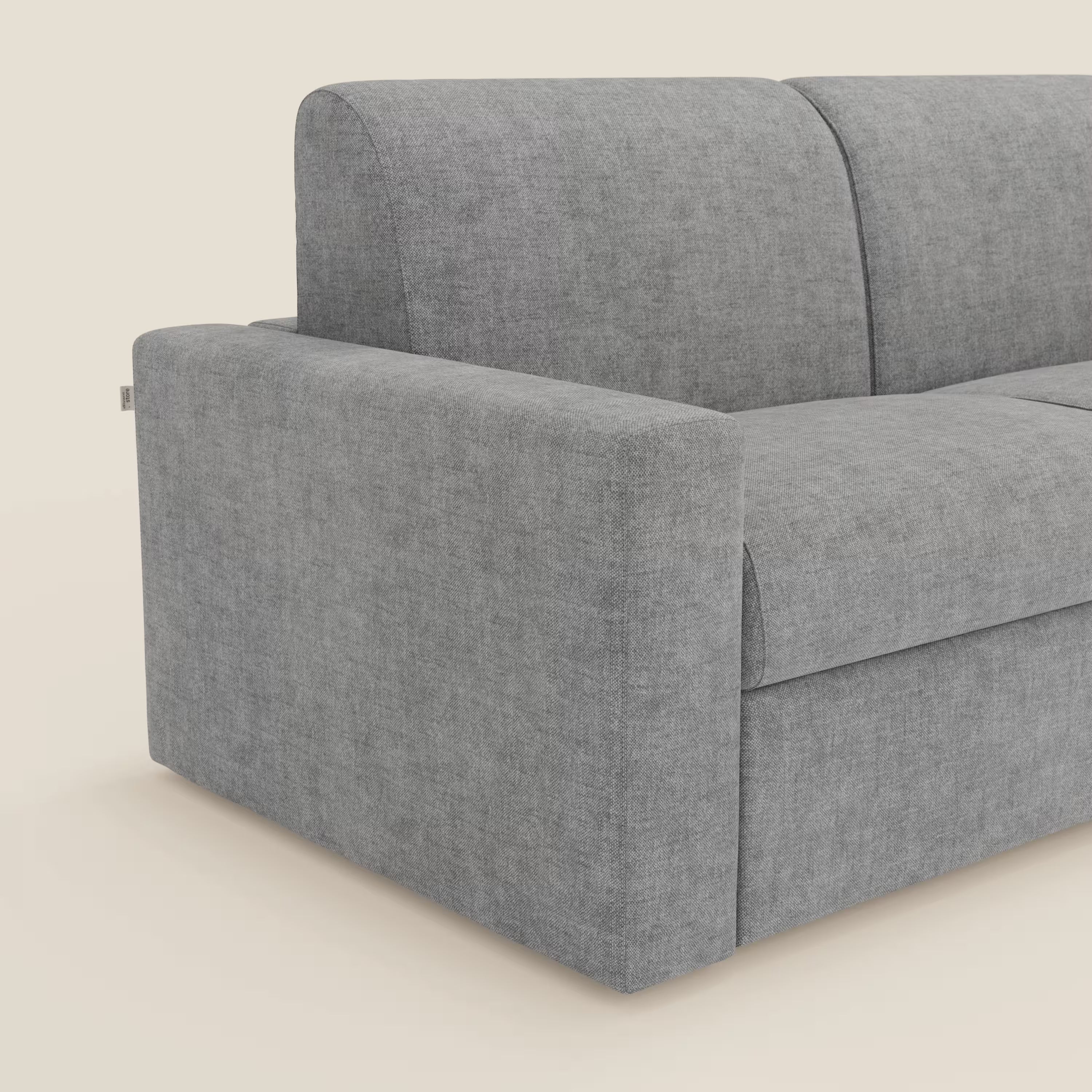 Un primo piano del Diomede Divano letto matrimoniale di Divani.Store in T35 grigio velluto easy clean mostra la sua moderna forma squadrata, il bracciolo sinistro e i cuscini dello schienale in tessuto morbido e strutturato su uno sfondo neutro.