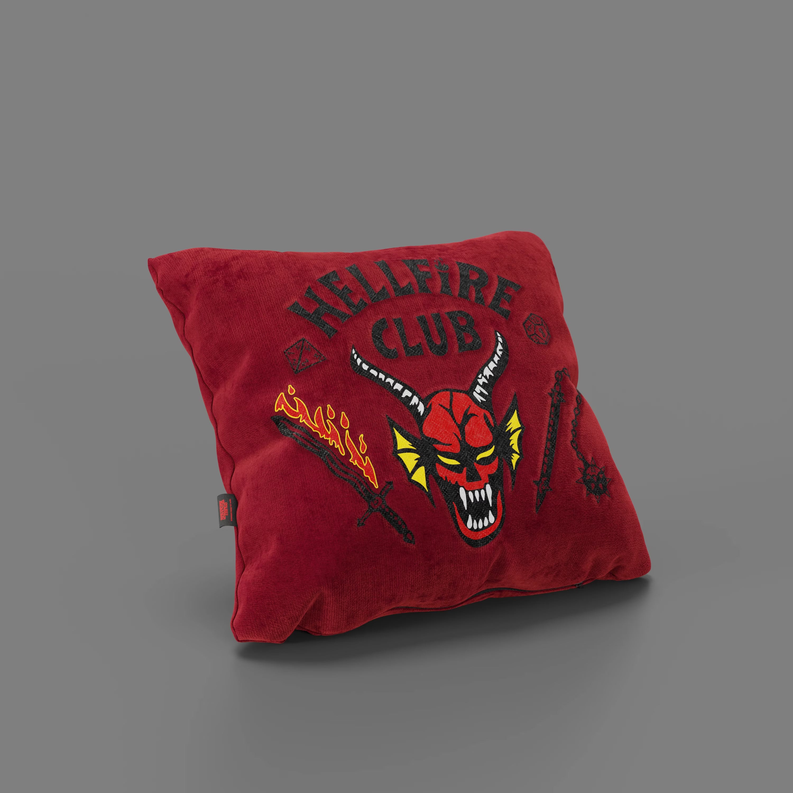 Il cuscino Cuscino Hellfire Club Stranger Things in edizione limitata di Divani.Store è caratterizzato da un tessuto rosso antimacchia (45x45 cm), dal ricamo "Hellfire Club", da un demone cornuto, da fiamme, spada e mazza su sfondo grigio.