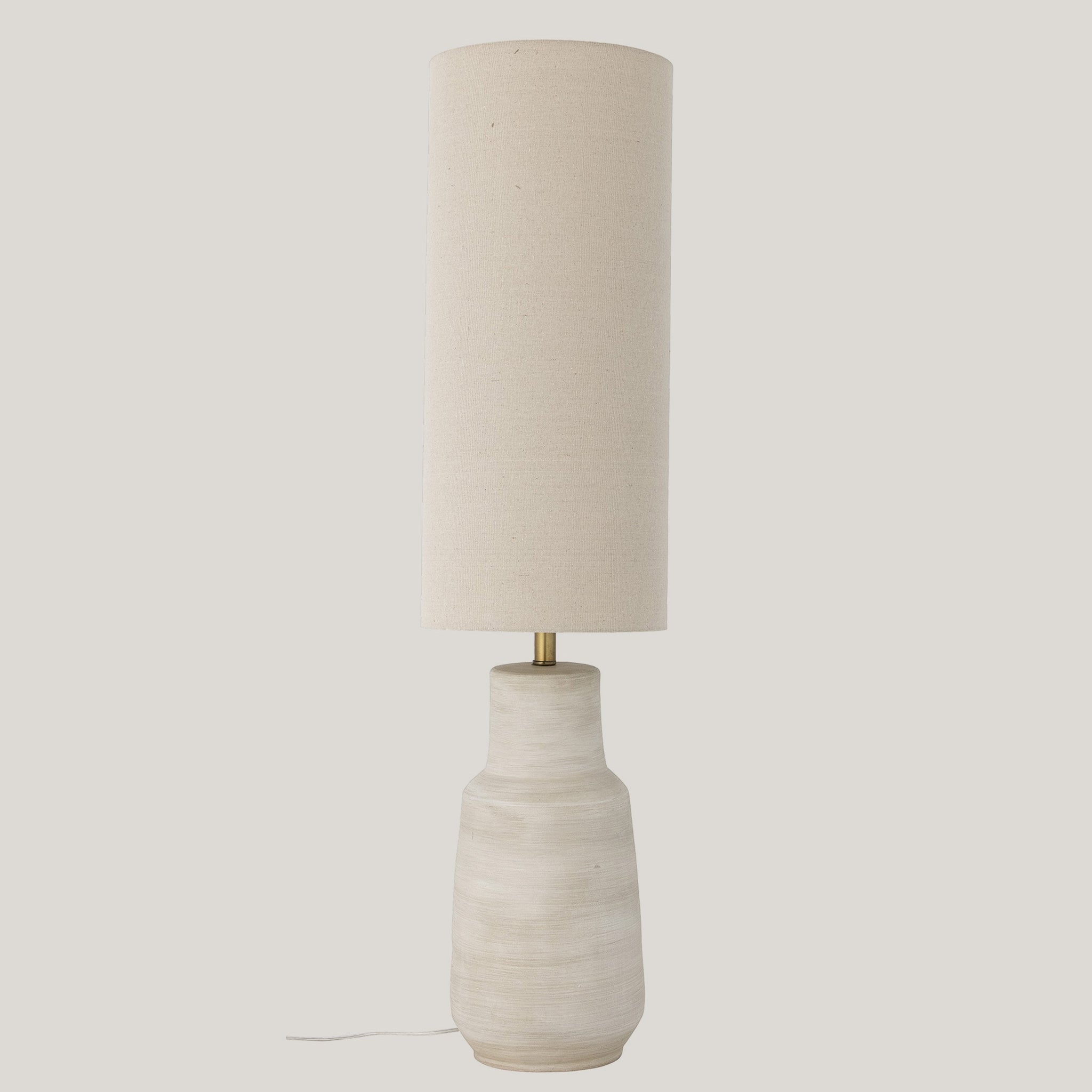 La lampada da terra Linetta con base in gres stoneware bianco di Divani.Store trasuda design raffinato con il suo aspetto alto e moderno. Presenta un paralume cilindrico in tessuto beige su una base in ceramica testurizzata bianco sporco e sfoggia un'estetica minimalista con una sottile asta di metallo che collega il paralume e la base. Su uno sfondo bianco semplice, include un cavo di alimentazione che si estende dalla base.