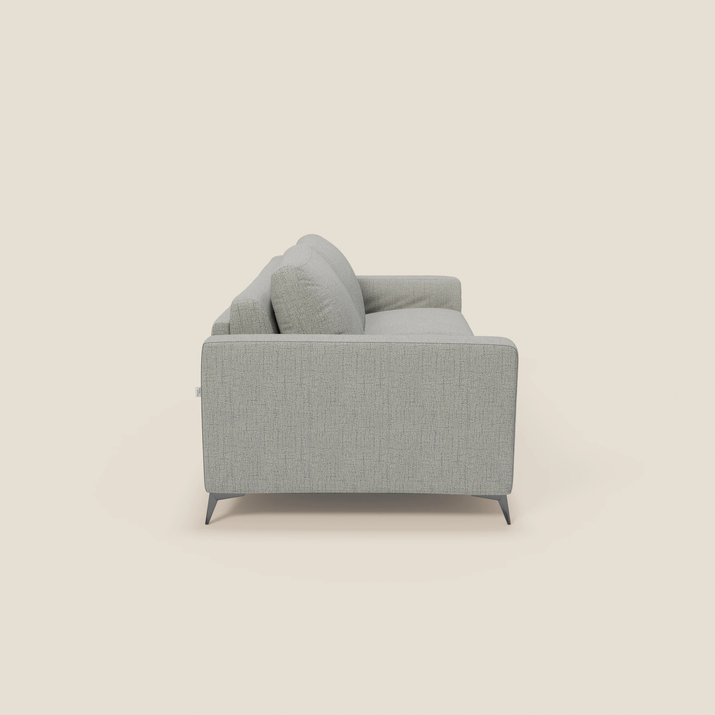 Il letto matrimoniale Alaya Divano di Divani.Store, presentato in tessuto impermeabile T03 grigio chiaro, è caratterizzato da cuscini morbidi, un unico bracciolo e gambe corte e angolate in metallo per un look minimal su uno sfondo crema.
