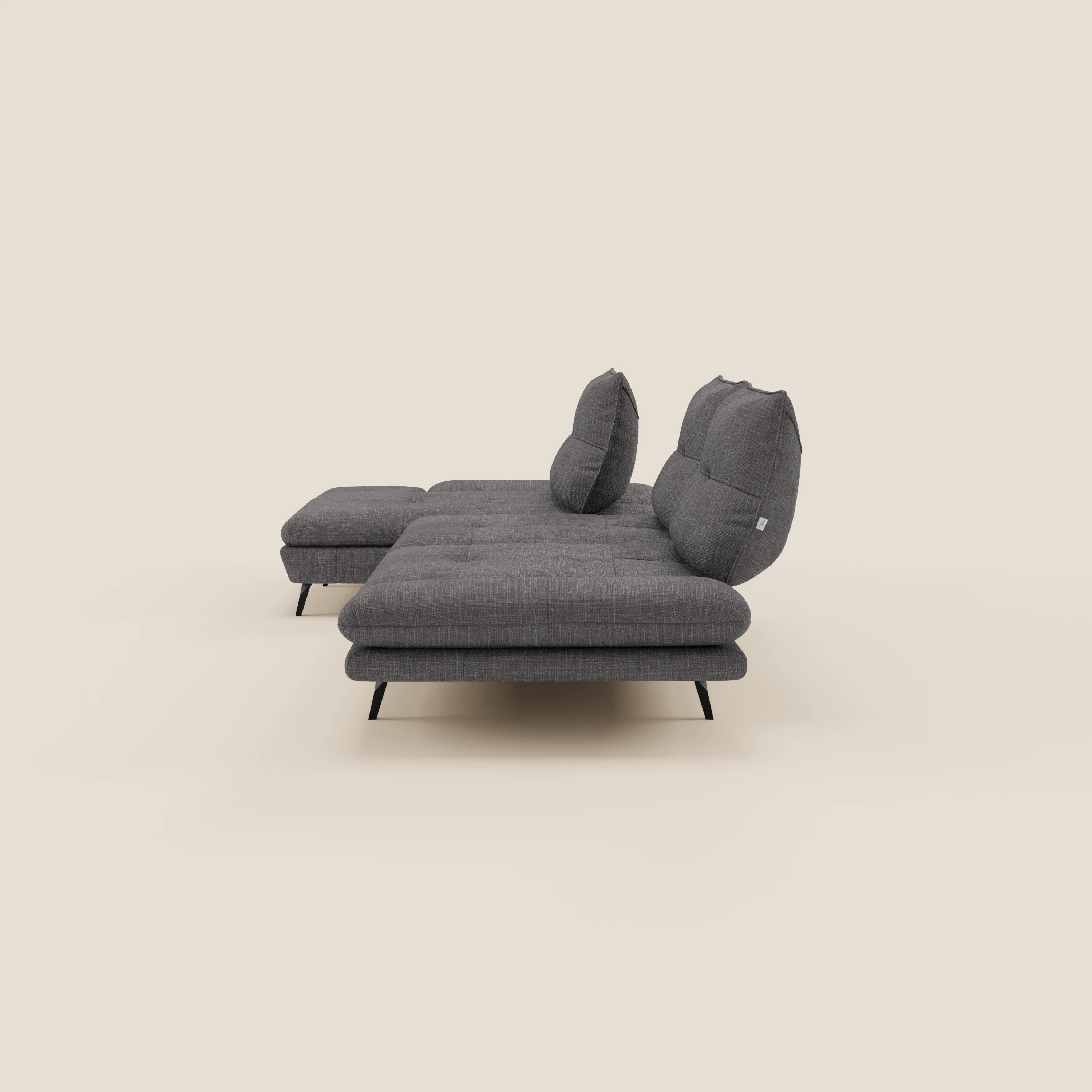 Ardex Divano con penisola di Divani.Store è presentato lateralmente in tessuto impermeabile T06 antracite, con schienali scorrevoli, braccioli regolabili, cuscini morbidi, gambe nere e chaise longue per un look moderno ed elegante.