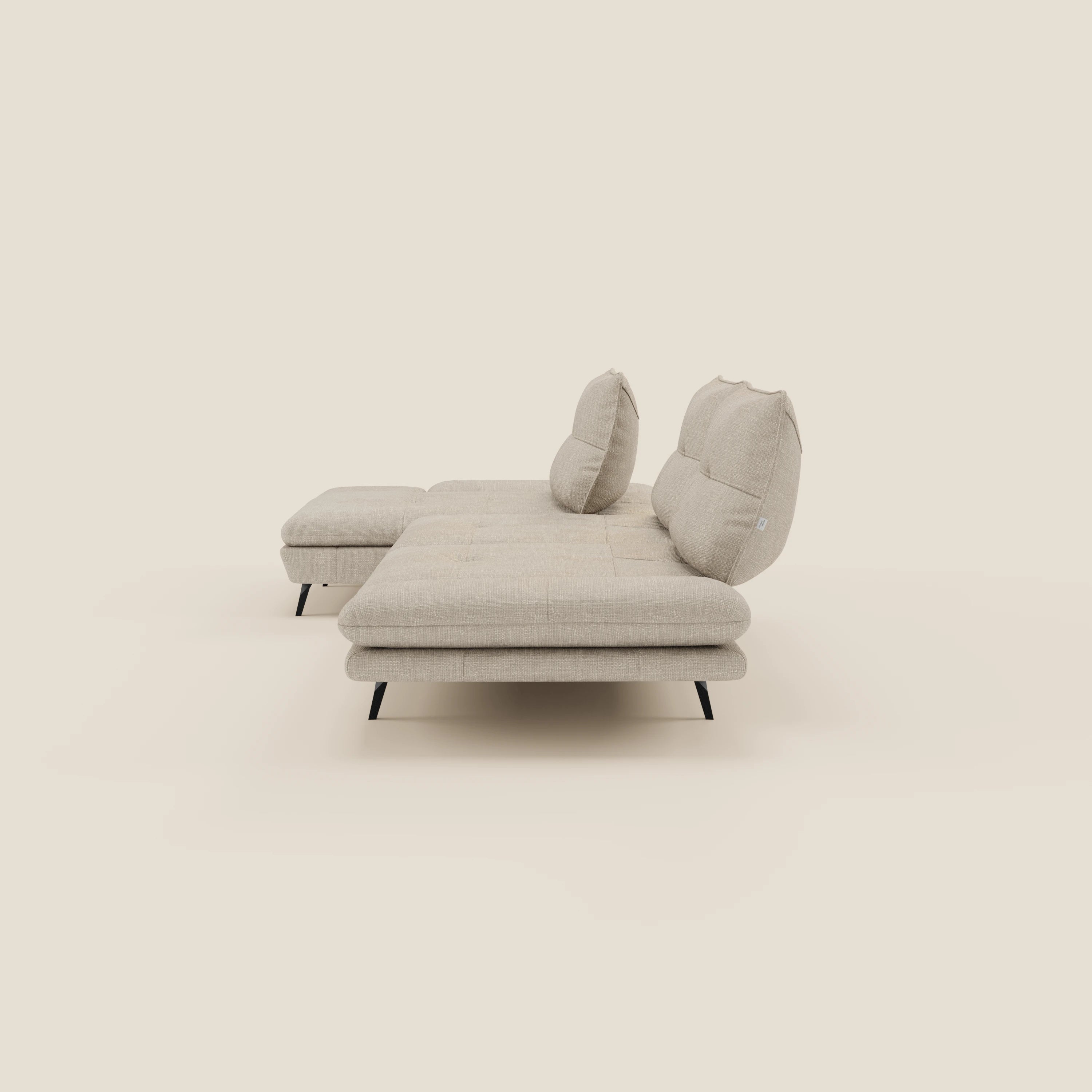 Ardex Divano con penisola di Divani.Store è caratterizzato da due schienali regolabili, braccioli mobili ed elegante tessuto impermeabile T06 panna. Il design moderno e le gambe angolari nere spiccano su uno sfondo crema chiaro.