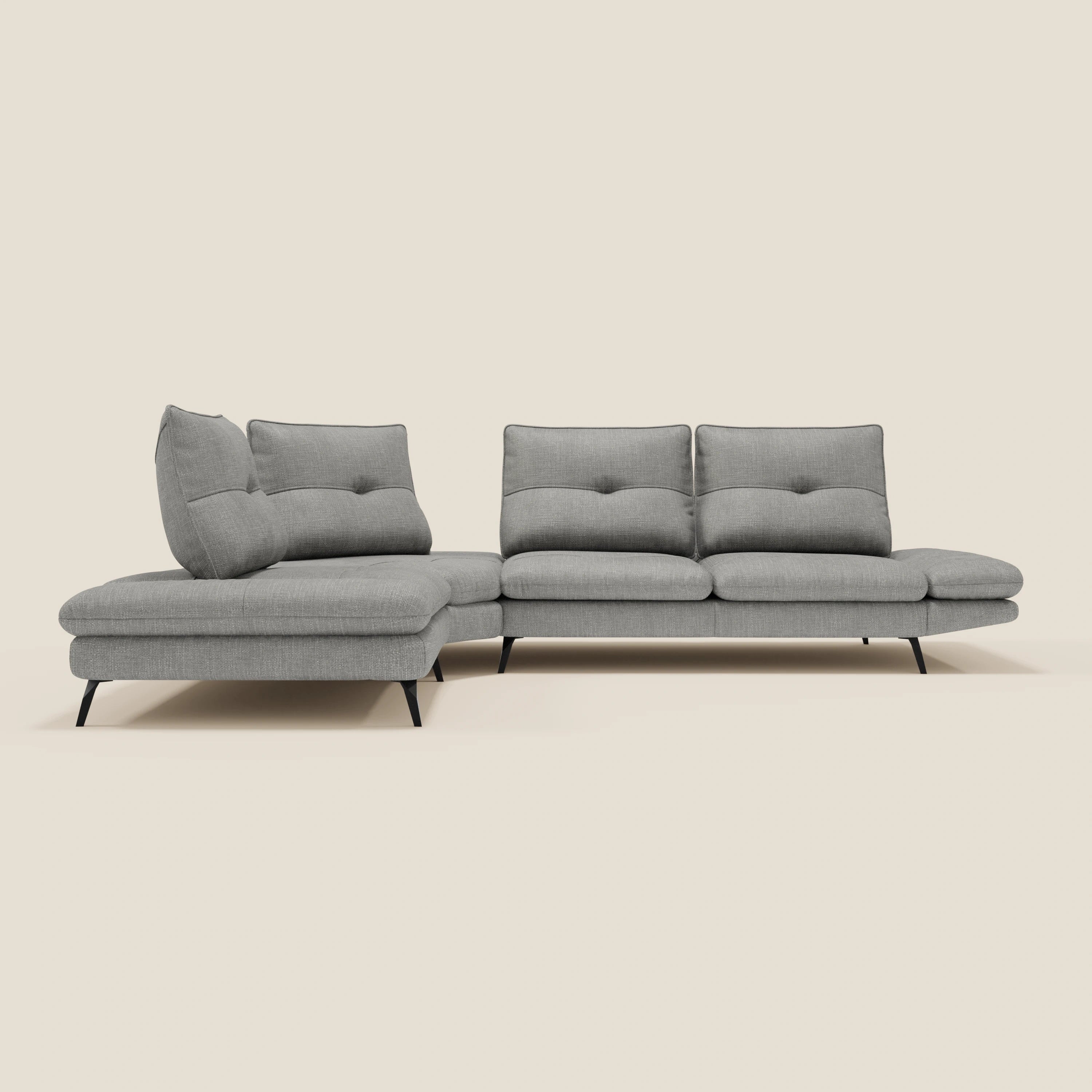 Ardex Divano Angolare di Divani.Store è un moderno divano angolare grigio chiaro in tessuto impermeabile T06, caratterizzato da tre sedute, una chaise sinistra, schienali trapuntati con poggiatesta e braccioli regolabili e sottili gambe in metallo nero su sfondo crema.