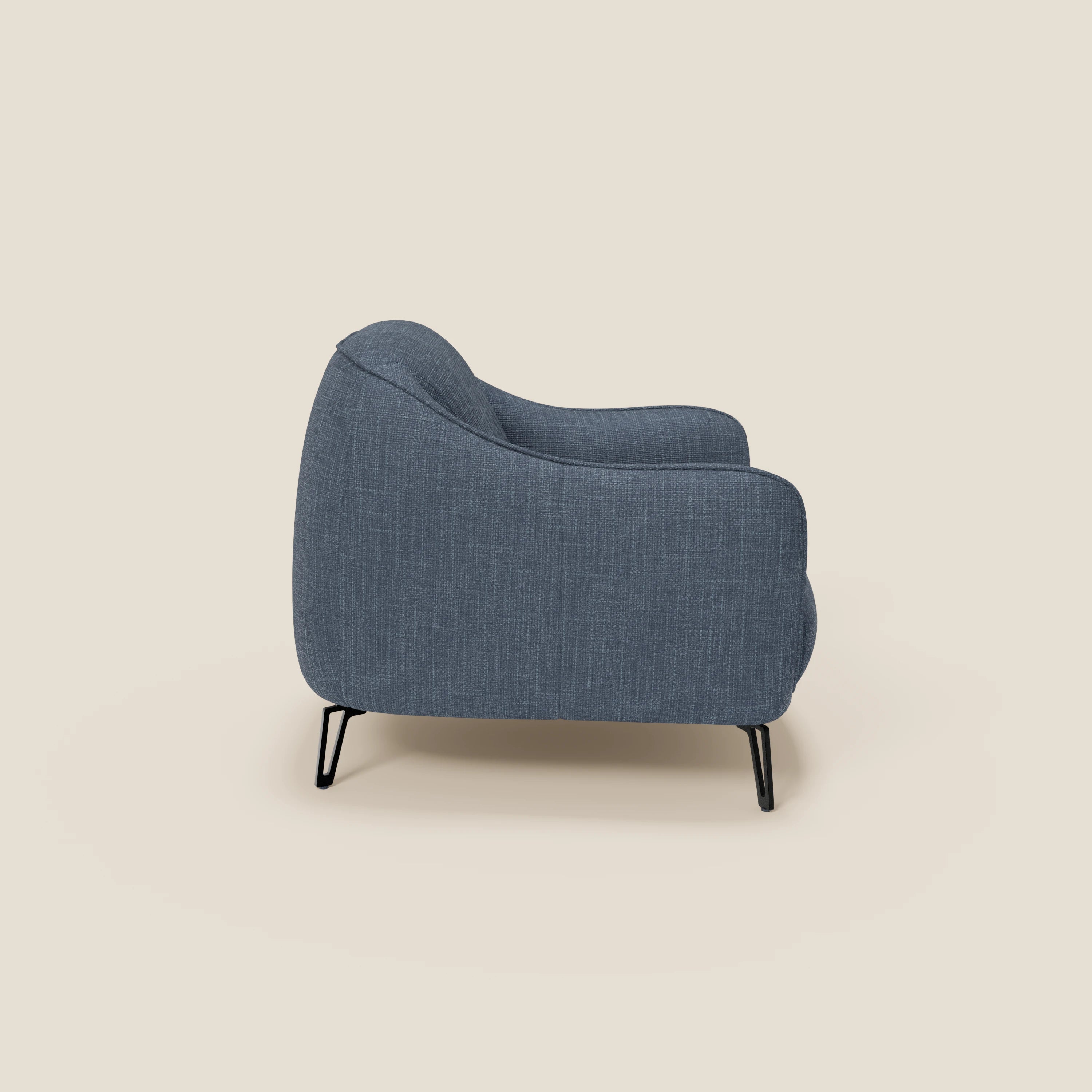 La poltroncina Avela di Divani.Store, dal comfort senza tempo, è rivestita in morbido tessuto impermeabile T06 blu e presenta schienale curvo, braccioli arrotondati e sottili gambe nere in metallo su sfondo crema chiaro.