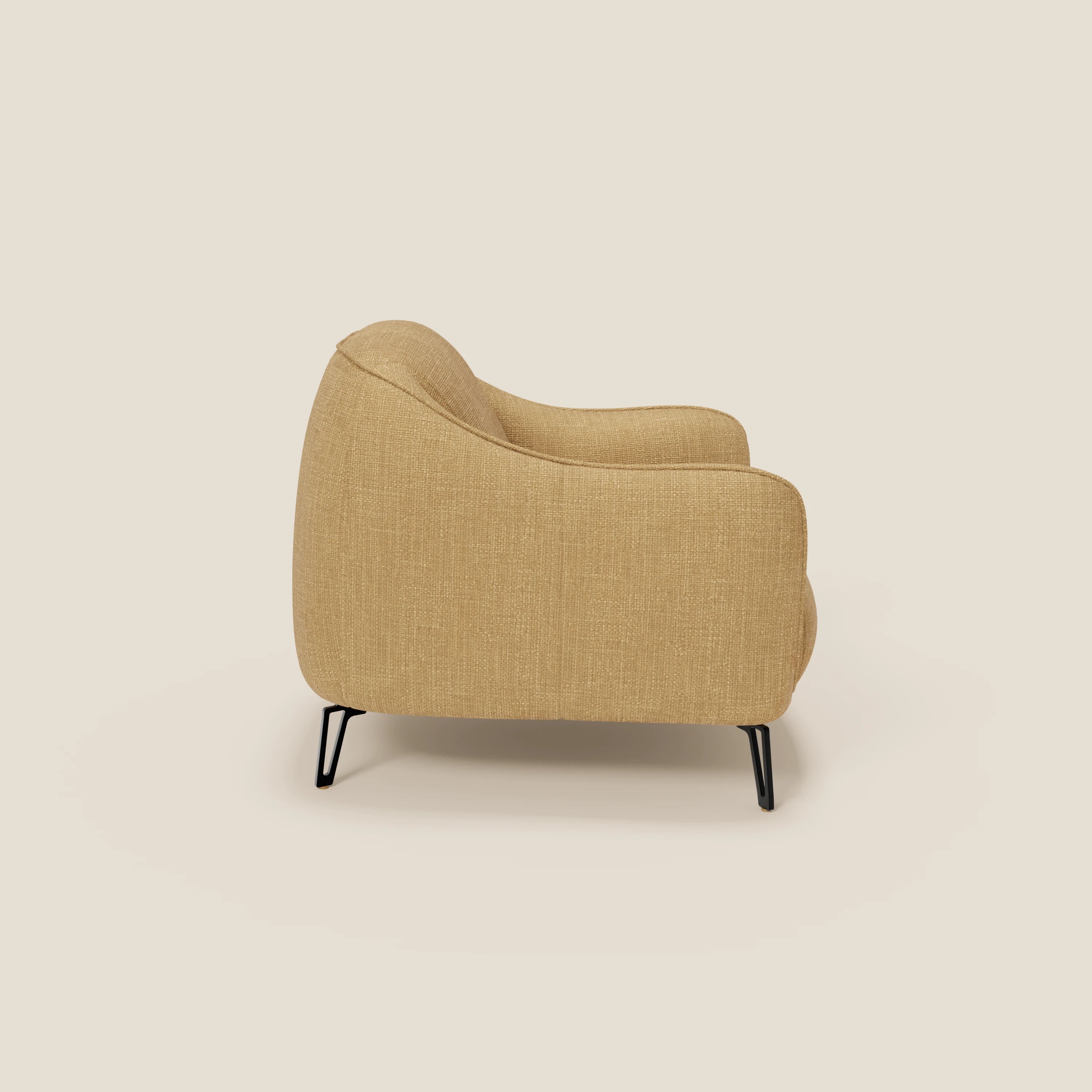 Avela Poltroncina di Divani.Store è vista di lato, rivestita in morbido tessuto impermeabile giallo T06. Presenta un design confortevole e senza tempo, con bordi arrotondati, sottili gambe in metallo nero e un look moderno su uno sfondo bianco sporco.