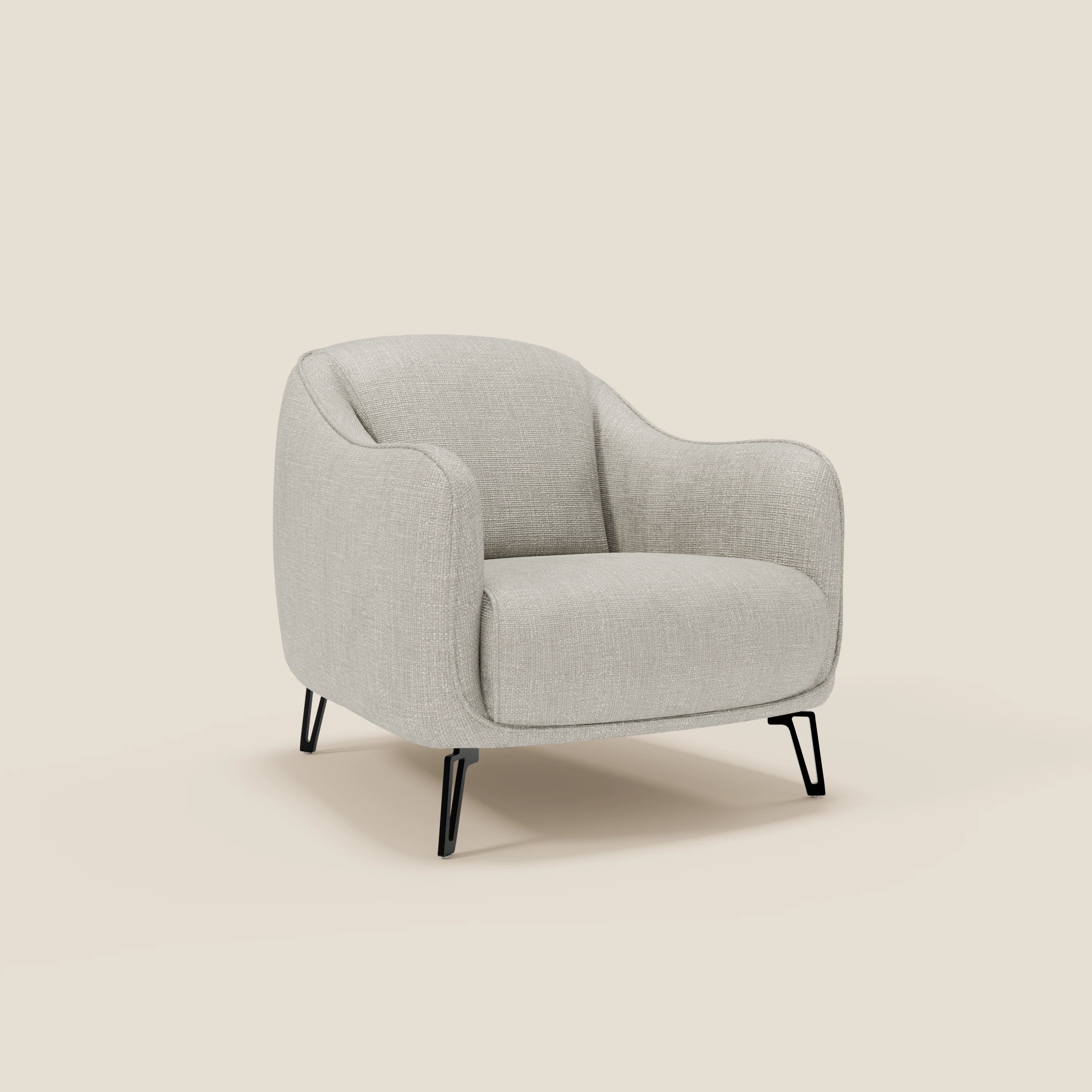 Avela Poltroncina di Divani.Store è caratterizzata da un comfort senza tempo in morbido tessuto impermeabile T06 grigio chiaro con bordi arrotondati, ampia seduta e schienale, braccioli svasati e quattro sottili gambe in metallo nero su sfondo crema.