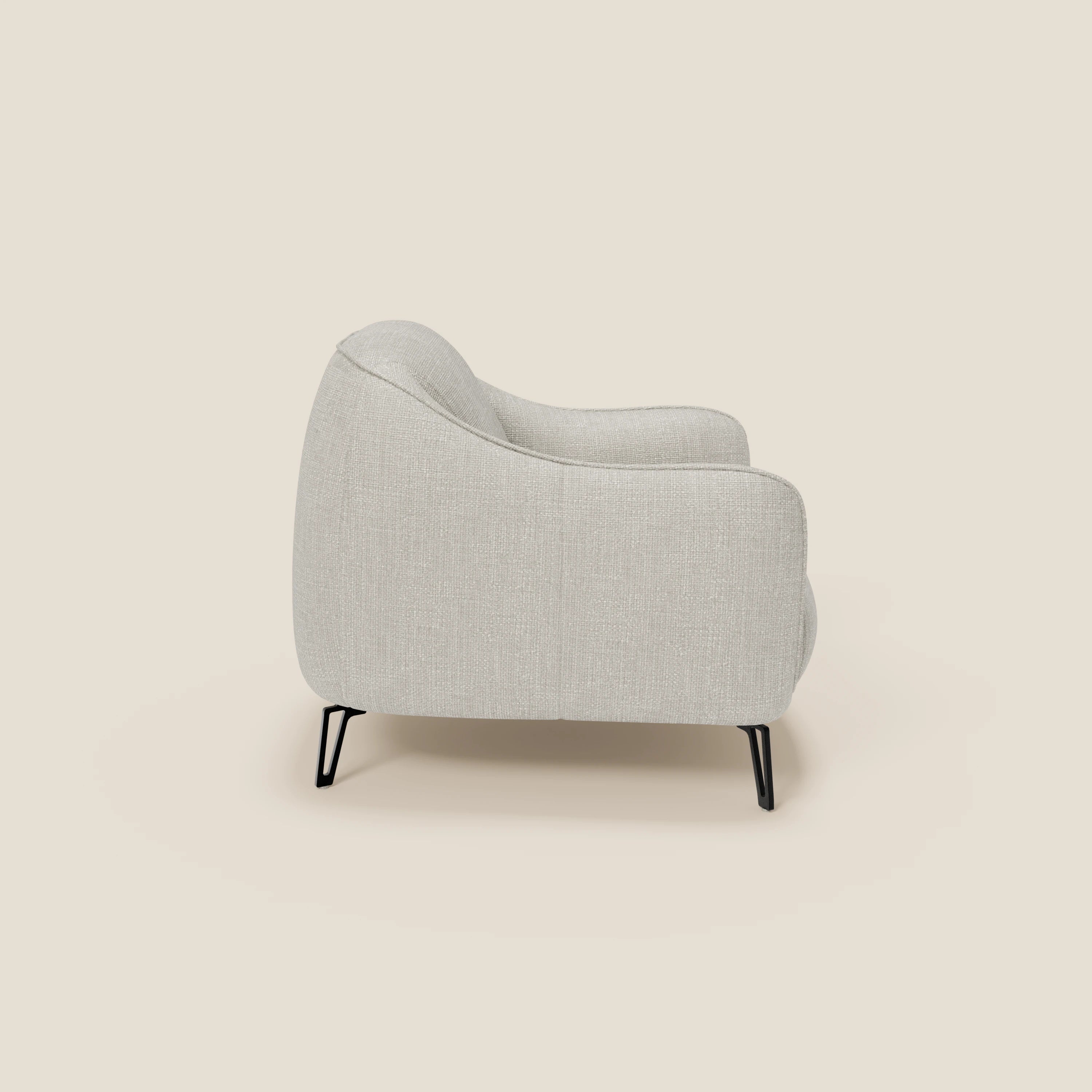 Vista laterale di Avela Poltroncina di Divani.Store, caratterizzata da un comfort senza tempo in morbido tessuto impermeabile T06 grigio chiaro, con schienale e braccioli arrotondati, sottili gambe in metallo nero, su uno sfondo neutro.