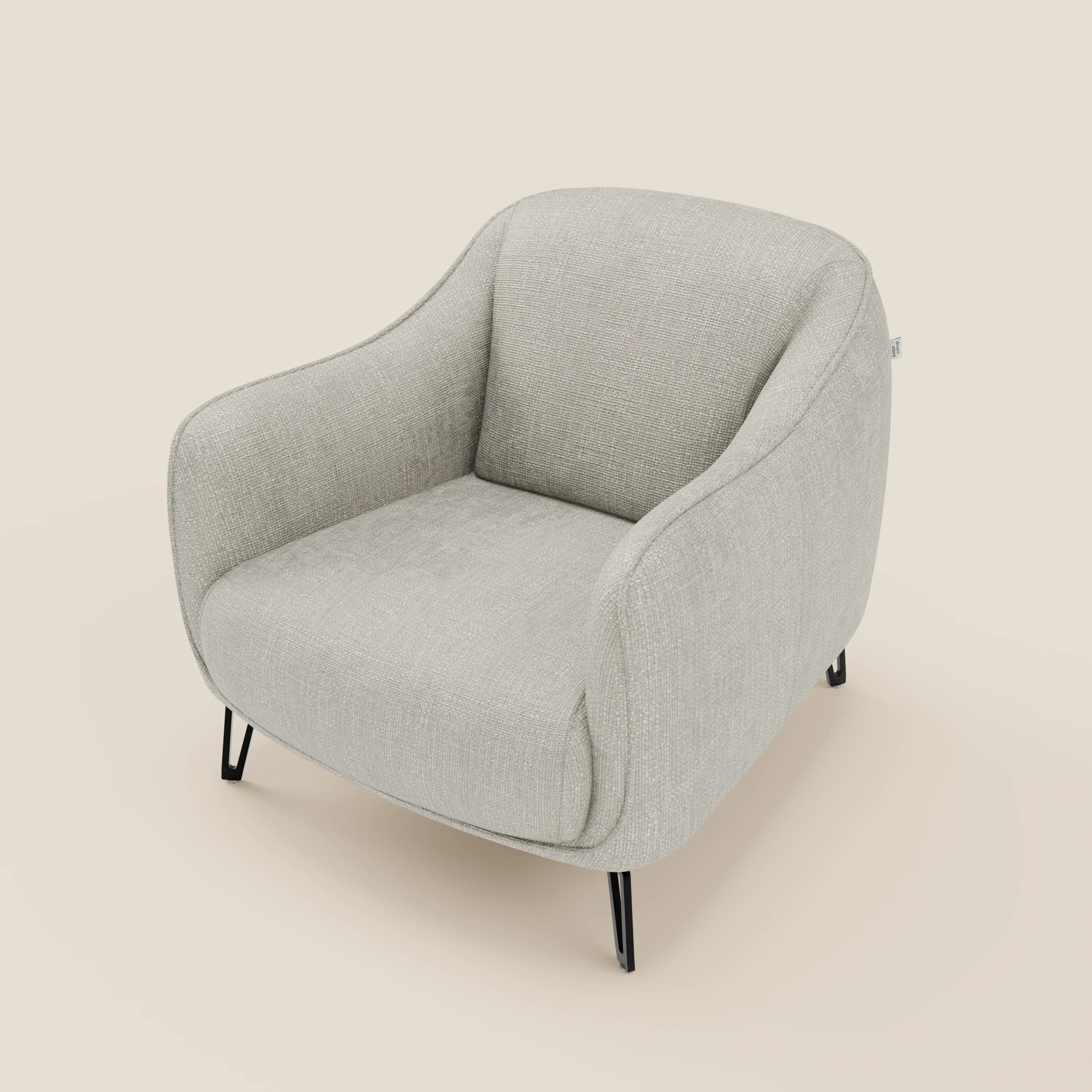 Avela Poltroncina di Divani.Store offre un comfort senza tempo grazie ai braccioli curvi e imbottiti, all'ampia seduta e alle sottili gambe in metallo nero rivestite in morbido tessuto impermeabile T06 grigio chiaro su sfondo beige.