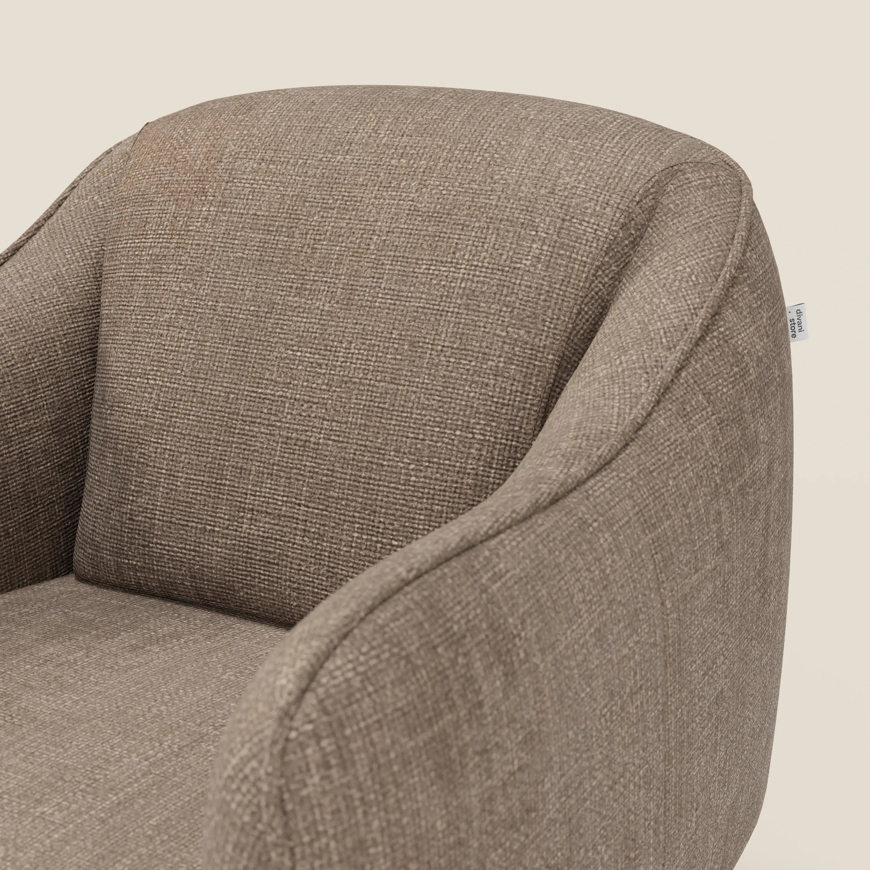 Primo piano di Avela Poltroncina di Divani.Store, con schienale e braccioli curvi in tessuto impermeabile T06 marrone; una piccola etichetta in tessuto sottolinea la cucitura posteriore su uno sfondo chiaro.
