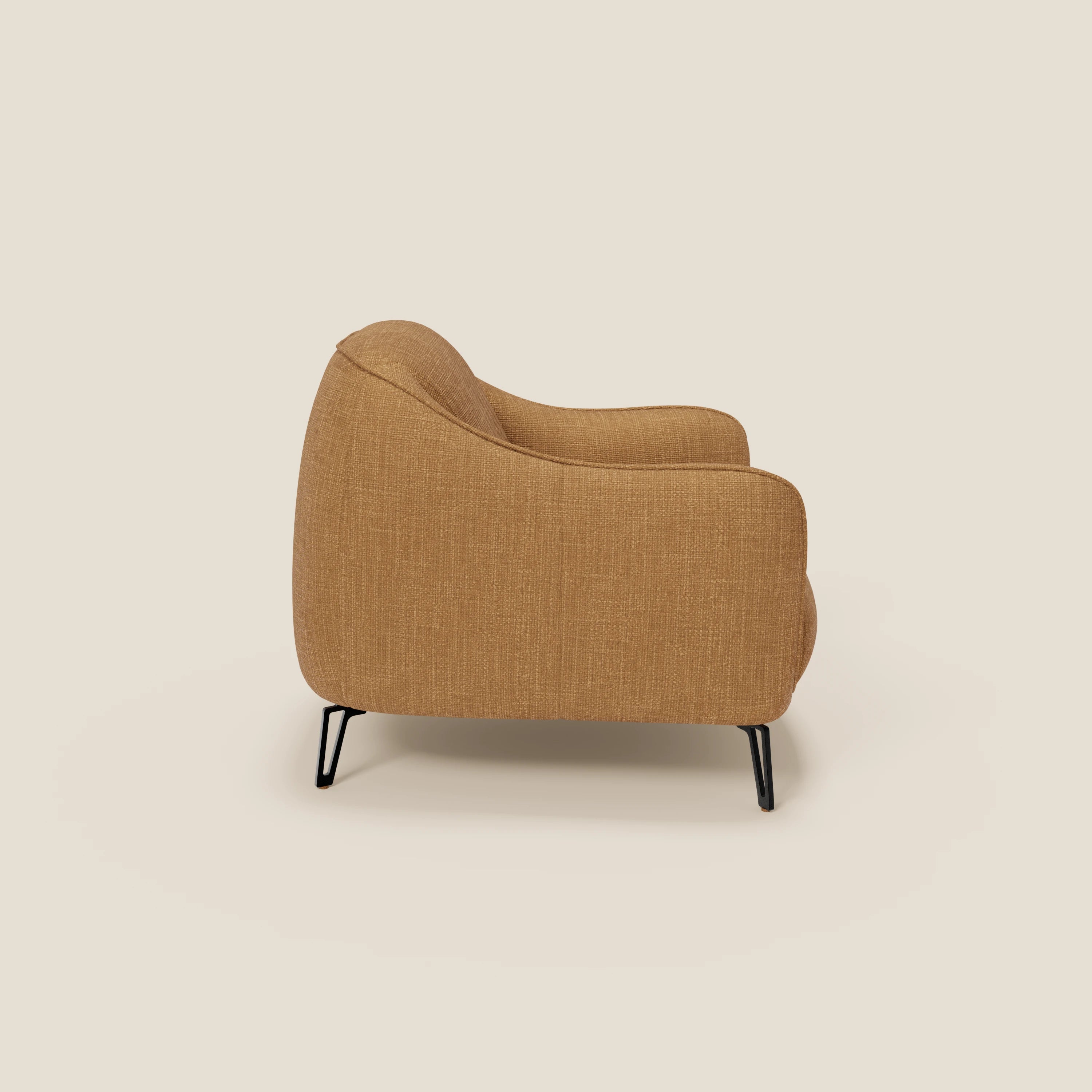 La poltroncina Avela di Divani.Store, presentata di profilo con un morbido tessuto impermeabile T06 ocra, è caratterizzata da uno schienale curvo, braccioli arrotondati e sottili gambe in metallo nero per un comfort senza tempo e un look minimalista su uno sfondo beige.