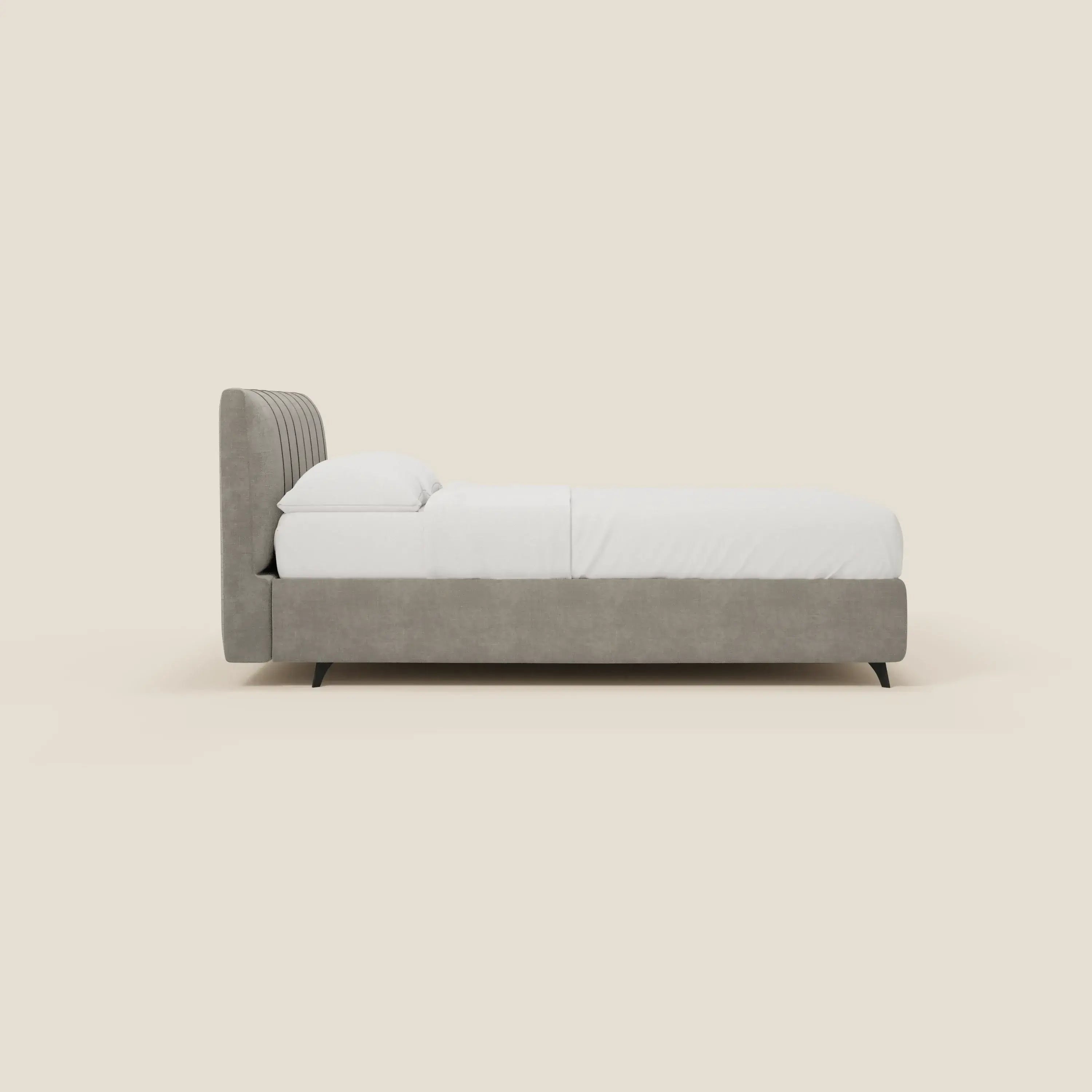 Il letto contenitore Bogart Edizione Grande Fratello di Letti.store è caratterizzato da un'alta testata con cuciture verticali in tessuto T22 grigio chiaro sfoderabile e antimacchia, elegantemente inserita in uno sfondo beige tinta unita che ne evidenzia il design italiano.