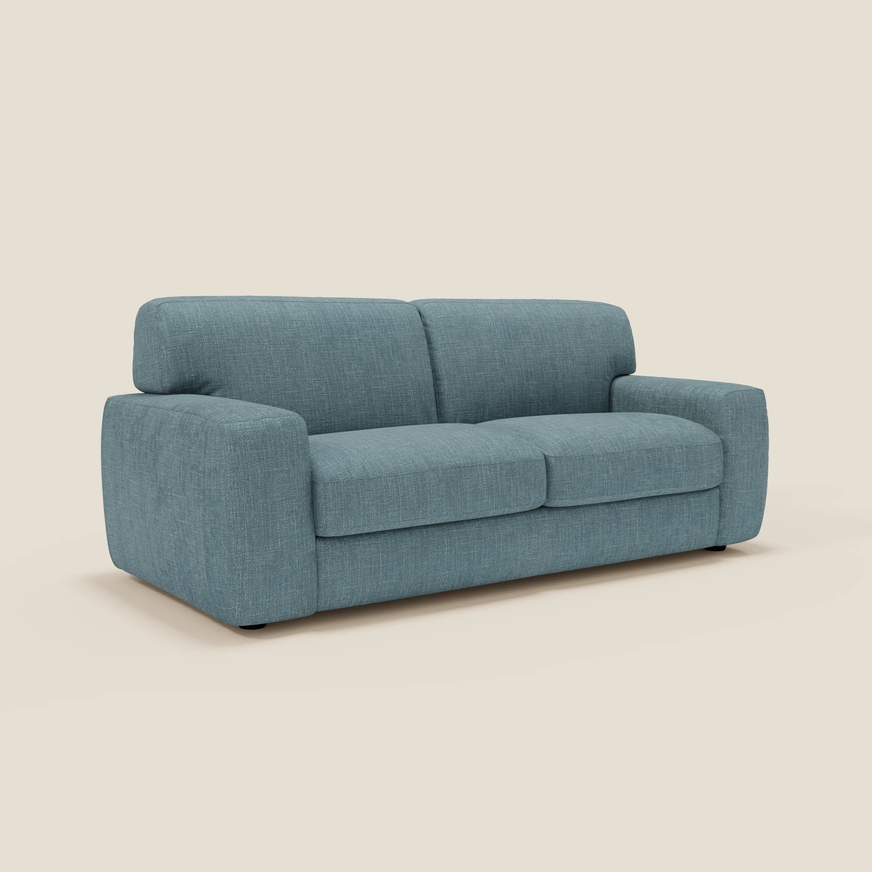 Cloud Divano letto materasso H17 cm di Divani.Store è un moderno biposto con rivestimento morbido e impermeabile in T06 azzurro, ampi braccioli, cuscini morbidi e schienale basso su discreti piedini neri su sfondo beige chiaro.