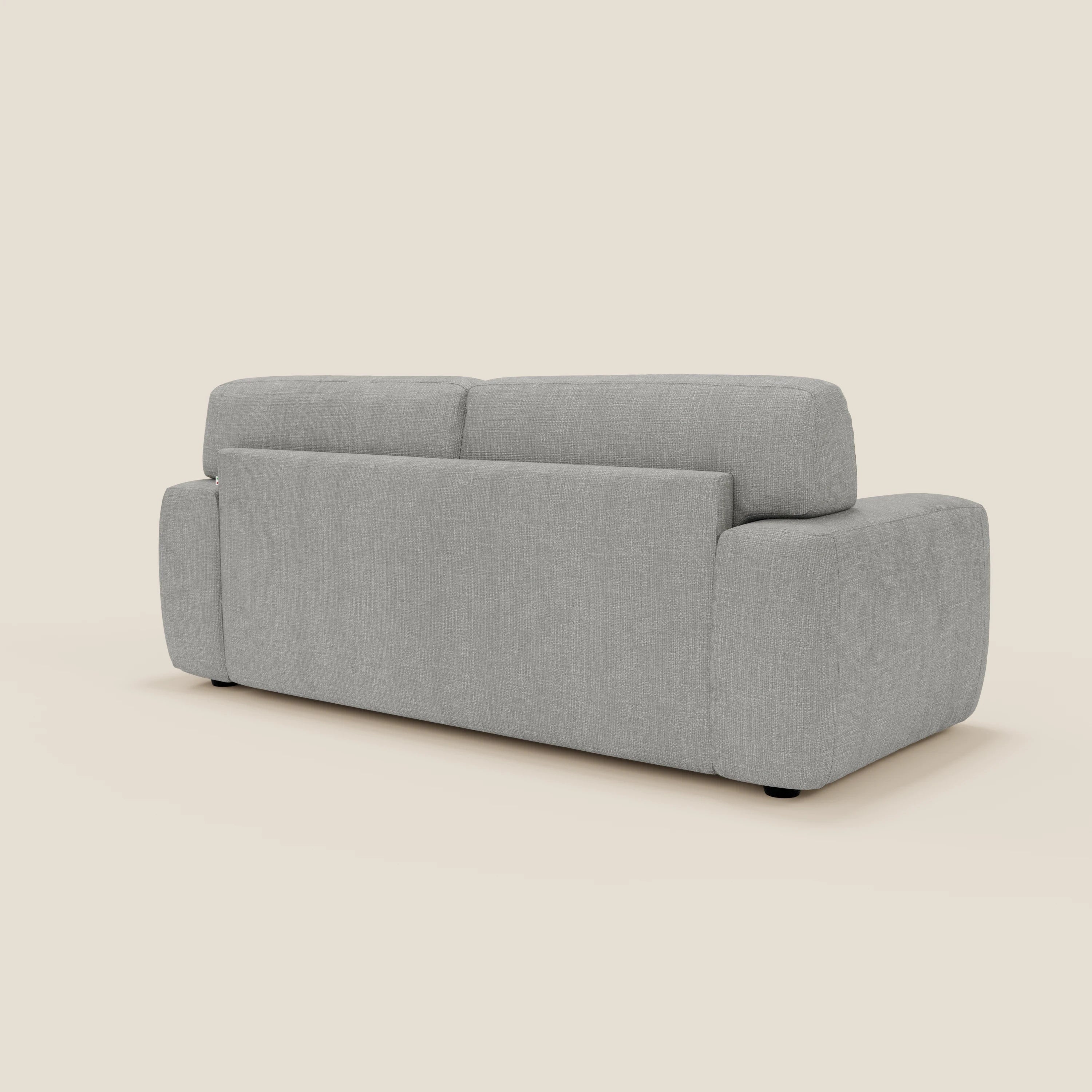 Il letto materasso Cloud Divano H17 cm di Divani.Store è visto da dietro in posizione angolata, con cuscini in feltro impermeabile grigio T06, braccioli larghi e bassi e piedini neri discreti su uno sfondo bianco sporco.