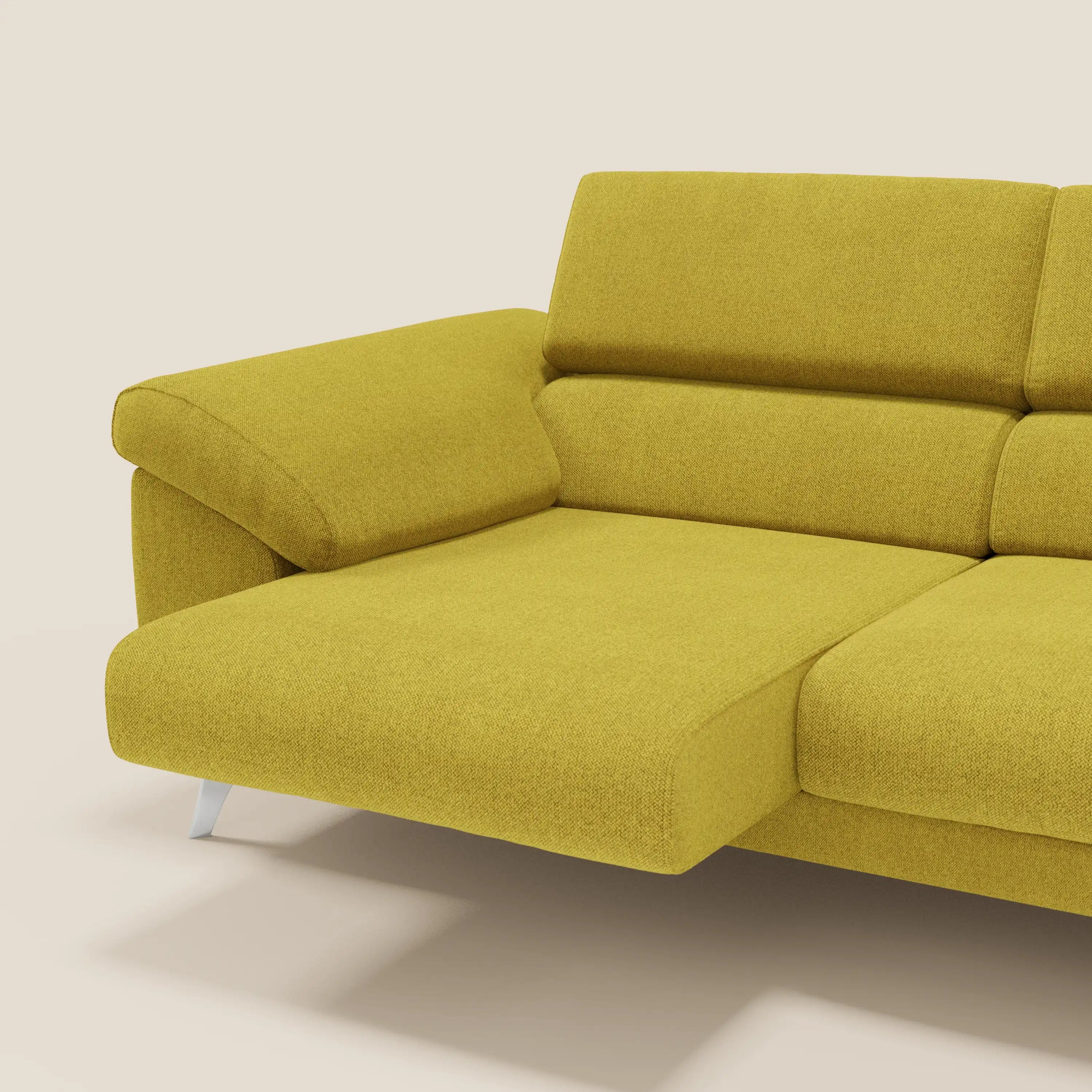 Primo piano del divano Donatello di Divani.Store in tessuto T23 giallo sole, con sedute allungabili, braccioli contenitore, poggiatesta reclinabili e gambe angolari in metallo, su sfondo beige.