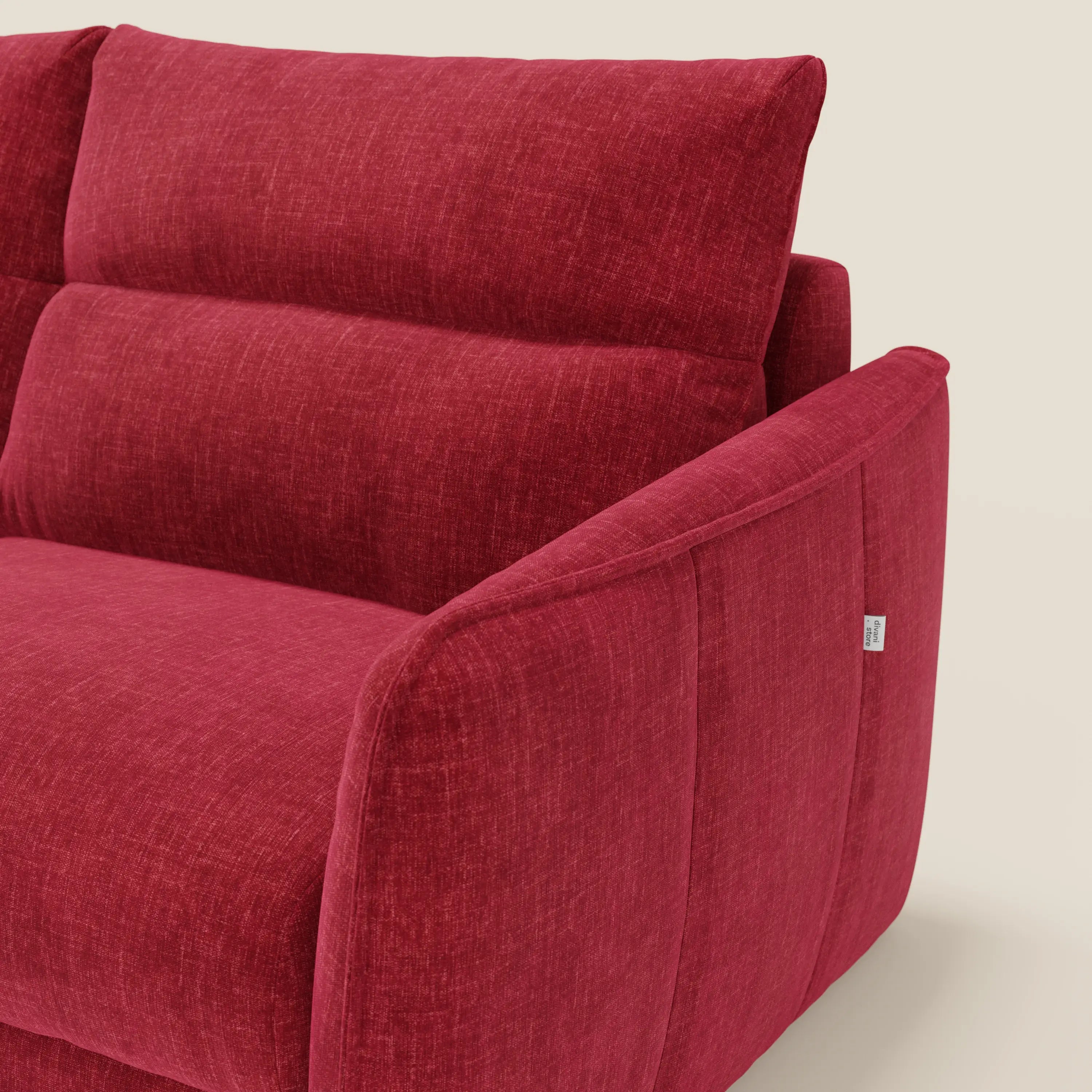Primo piano del letto Elios Divano di Divani.Store, caratterizzato da cuscini morbidi spalliera in tessuto smacchiabile T24 rosso bordeaux, braccioli angolati, cuciture sottili e una piccola etichetta bianca sul bracciolo su uno sfondo beige.