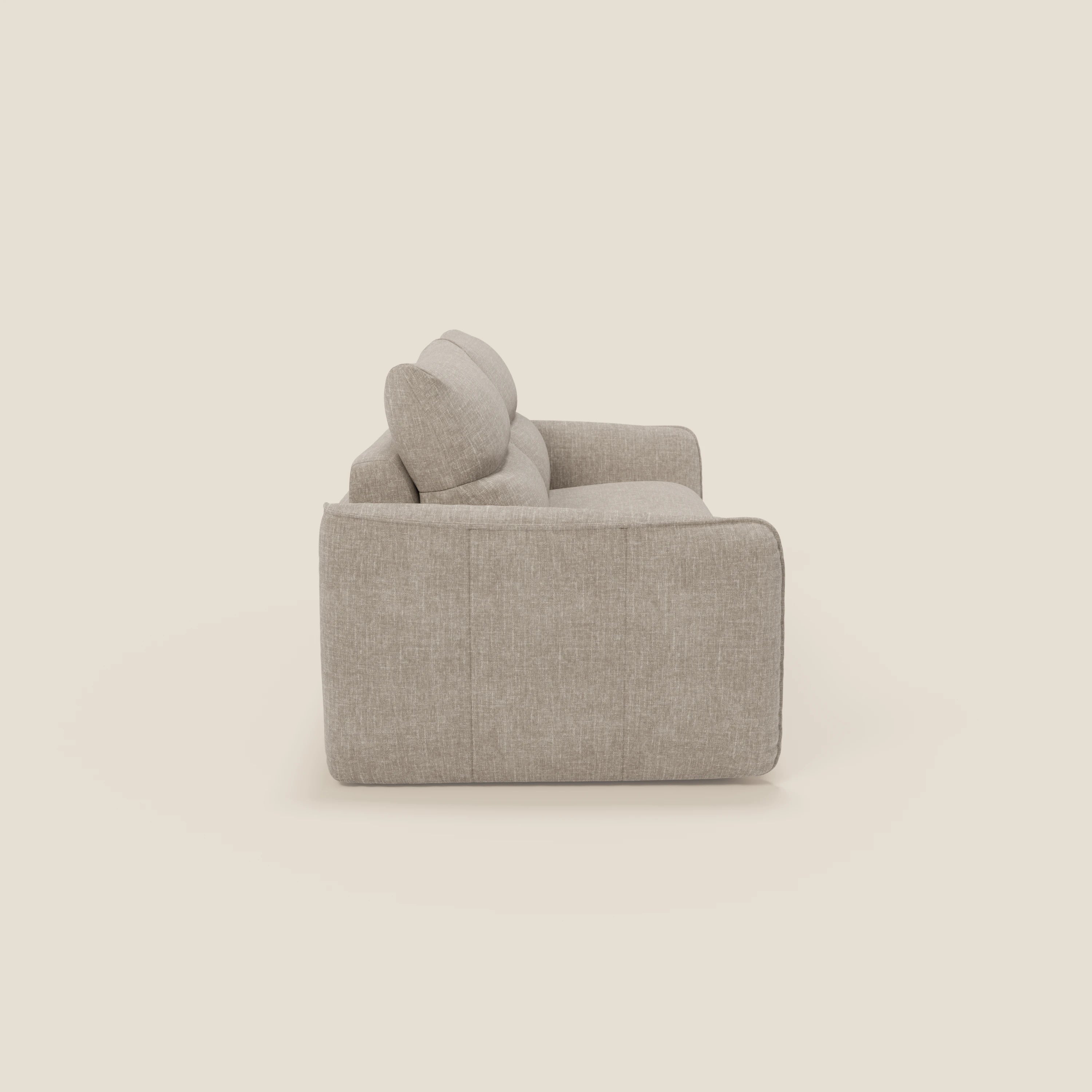 Il divano letto Elios di Divani.Store è presentato di lato su uno sfondo semplice, con morbidi cuscini spalliera in tessuto smacchiabile T24 lino chiaro, ampi braccioli imbottiti e un moderno design squadrato senza gambe a vista.