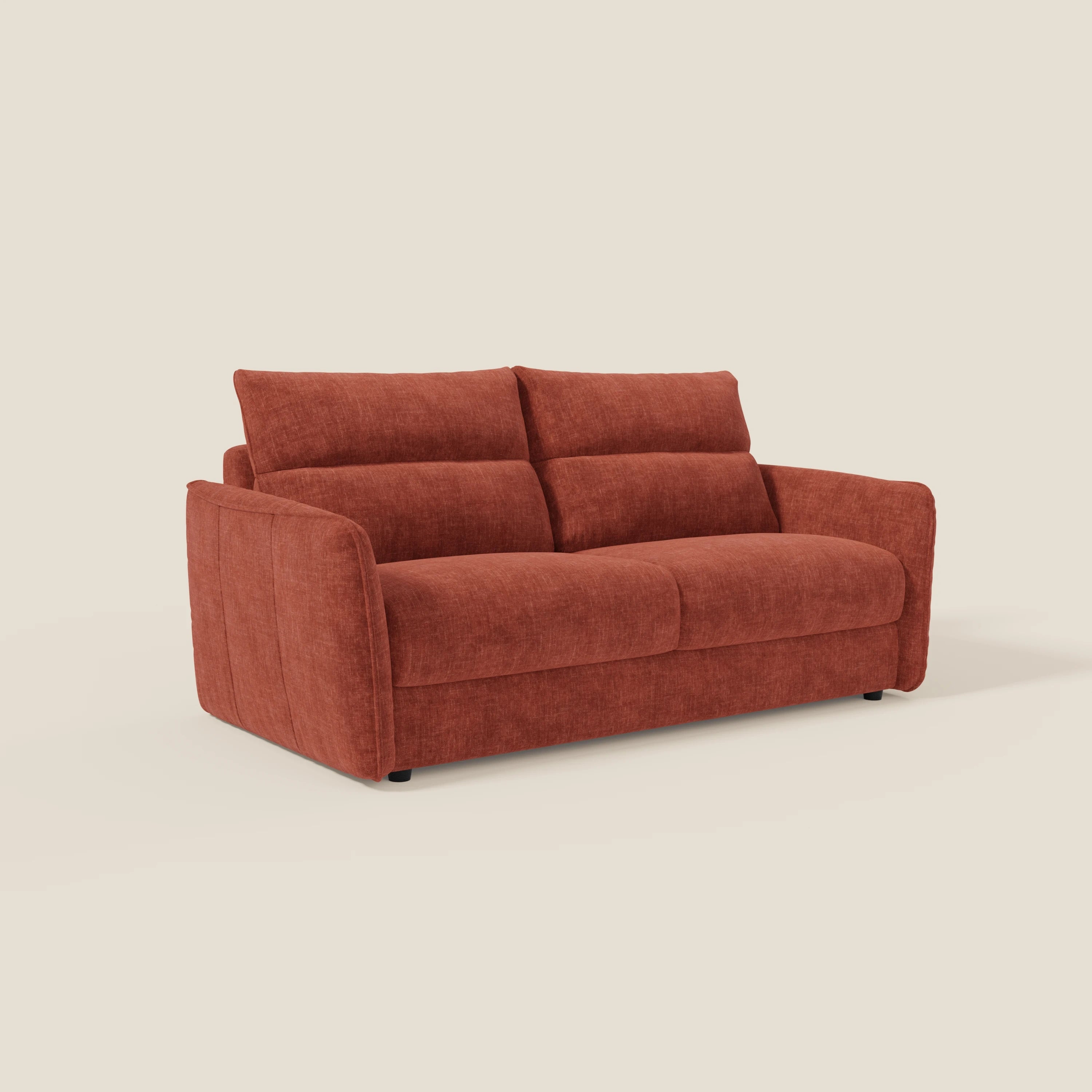 Il divano letto Elios di Divani.Store è caratterizzato da morbidi cuscini di schienale in tessuto antimacchia T24 ruggine, da una seduta morbida, da braccioli delicatamente svasati e da un design minimalista con gambe discrete, perfette su uno sfondo bianco sporco.