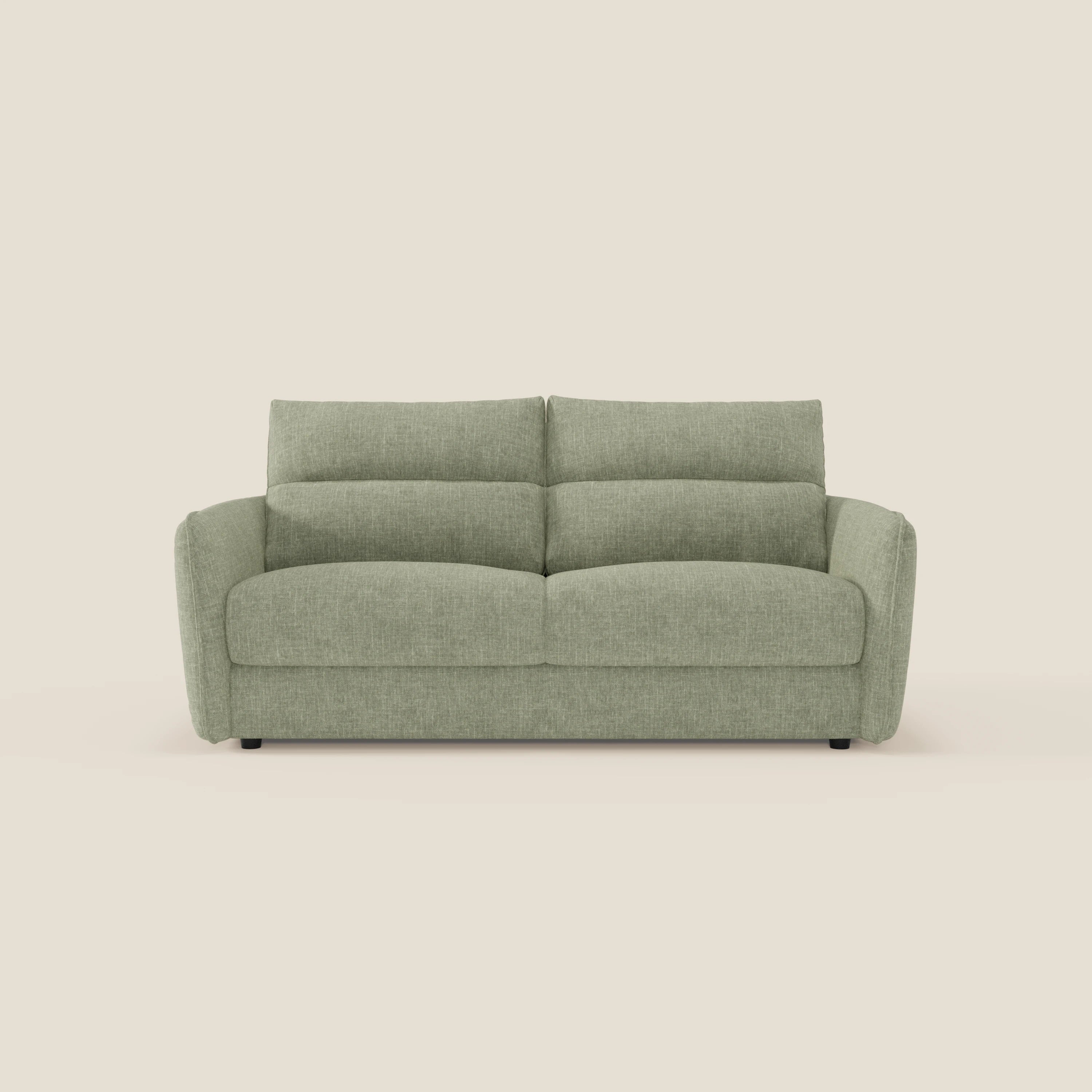 Elios Divano letto di Divani.Store è caratterizzato da morbidi cuscini di schienale in tessuto T24 verde salvia, antimacchia, due cuscini di seduta e di schienale, ampi braccioli, gambe corte nere e un look moderno su uno sfondo beige chiaro.
