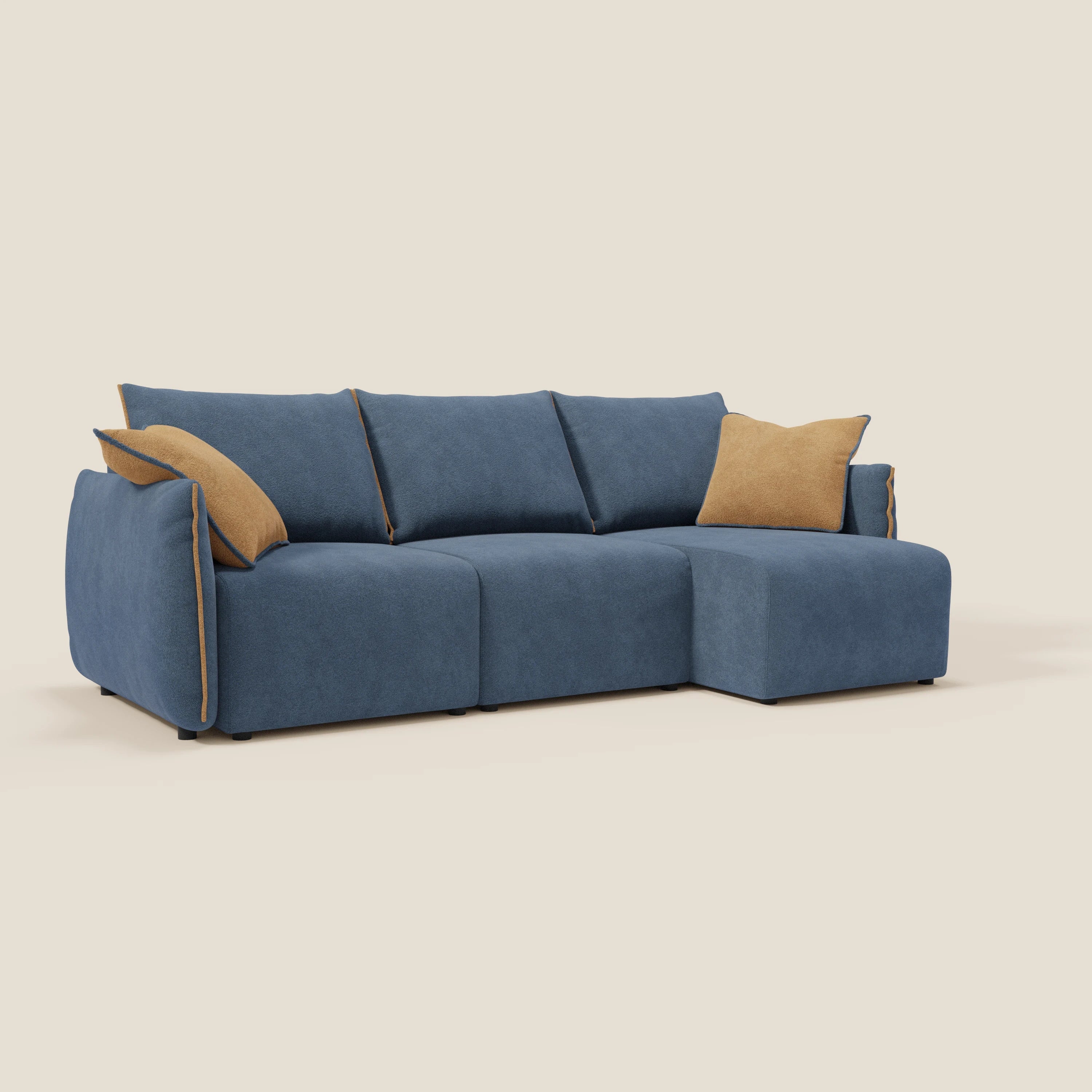 Il Divano angolare reversibile Flexar di Divani.Store ha tre posti a sedere, è dotato di sedute estensibili in morbido bouclé impermeabile blu T07 con accenti arancioni e comprende due cuscini color tan, su uno sfondo beige semplice.