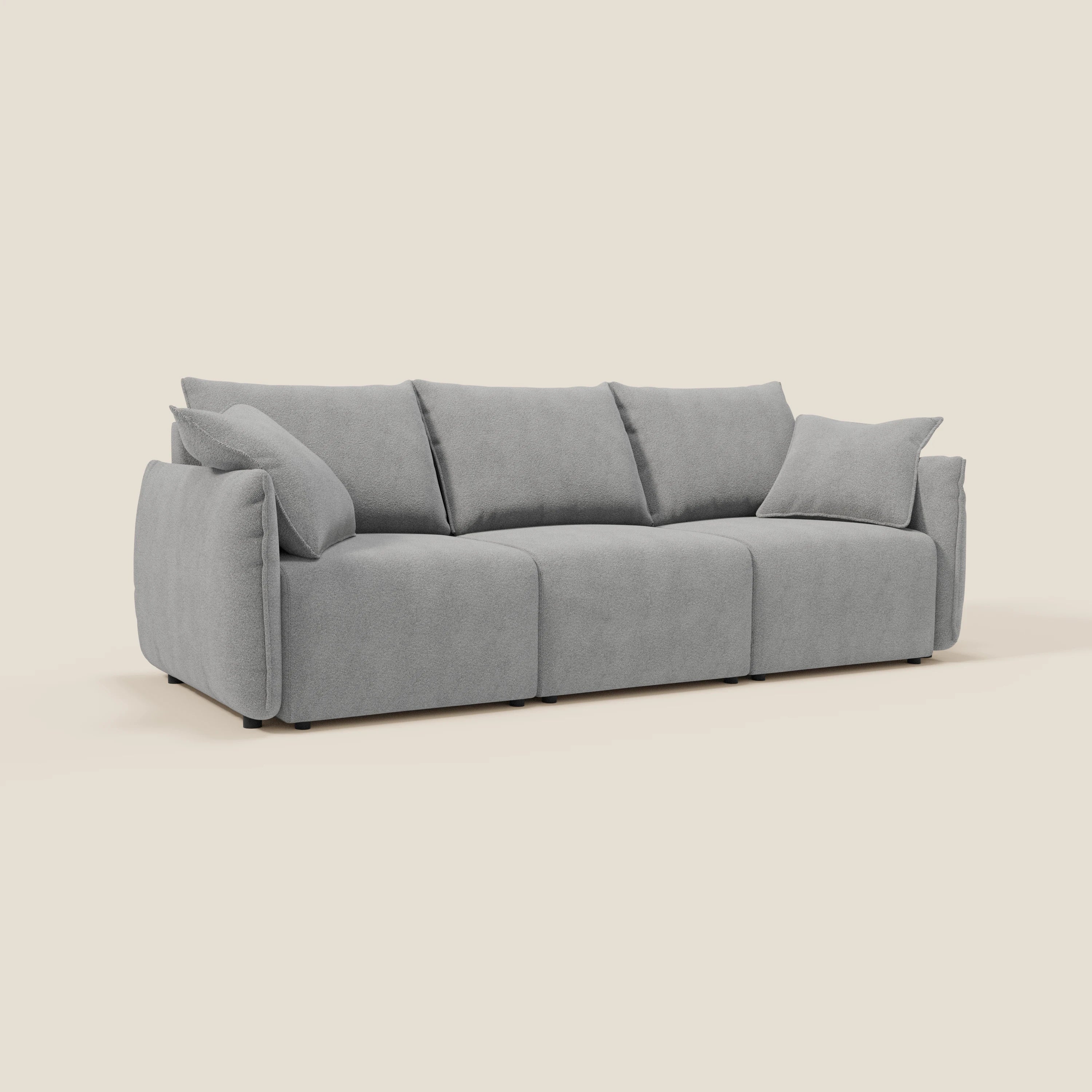 Il divano Flexar di Divani.Store è caratterizzato da 3 sedute allungabili, uno schienale in piuma d'oca, un rivestimento in bouclé impermeabile T07 grigio e cuscini laterali coordinati. Moderno e soffice, poggia su gambe scure su uno sfondo bianco sporco.