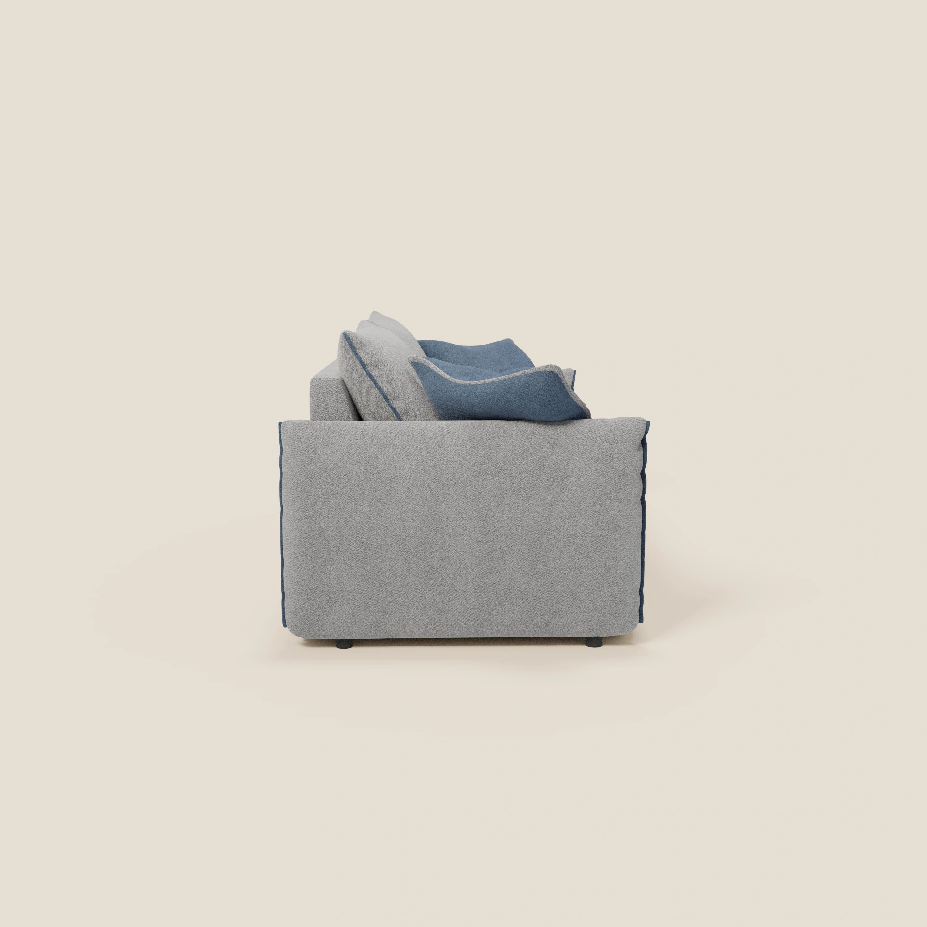 Vista laterale del divano Flexar con sedute allungabili e schienale in piuma di Divani.Store, in morbido bouclé impermeabile T07 grigio-blu, con cuscini d'accento blu. Linee pulite e cuscini in piuma d'oca creano un look contemporaneo e minimalista.