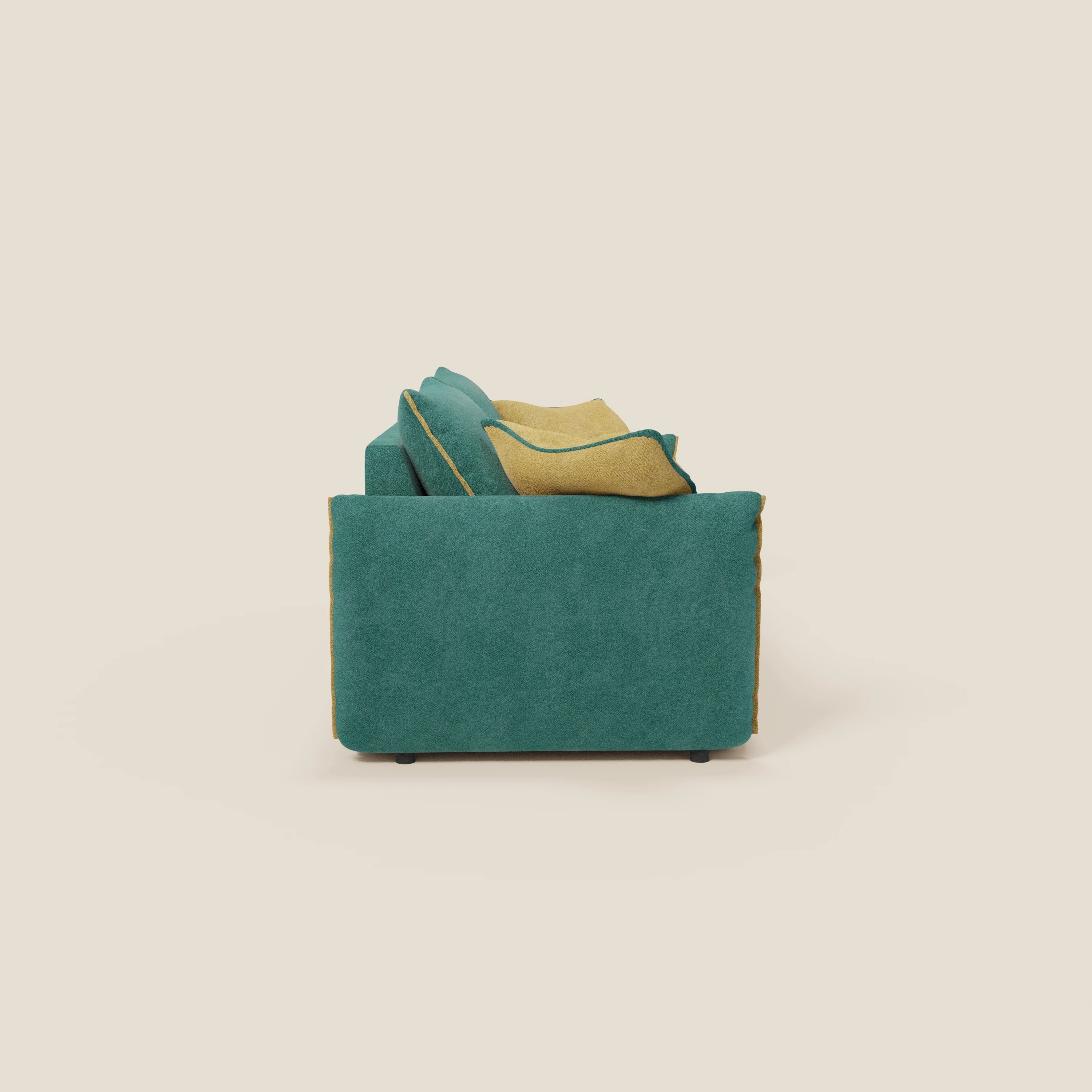 Vista laterale del divano Flexar con sedute allungabili e schienale in piuma di Divani.Store, presentato in bouclé impermeabile T07 verde-giallo con cuscini e profili giallo senape, gambe corte nere e sfondo crema chiaro.