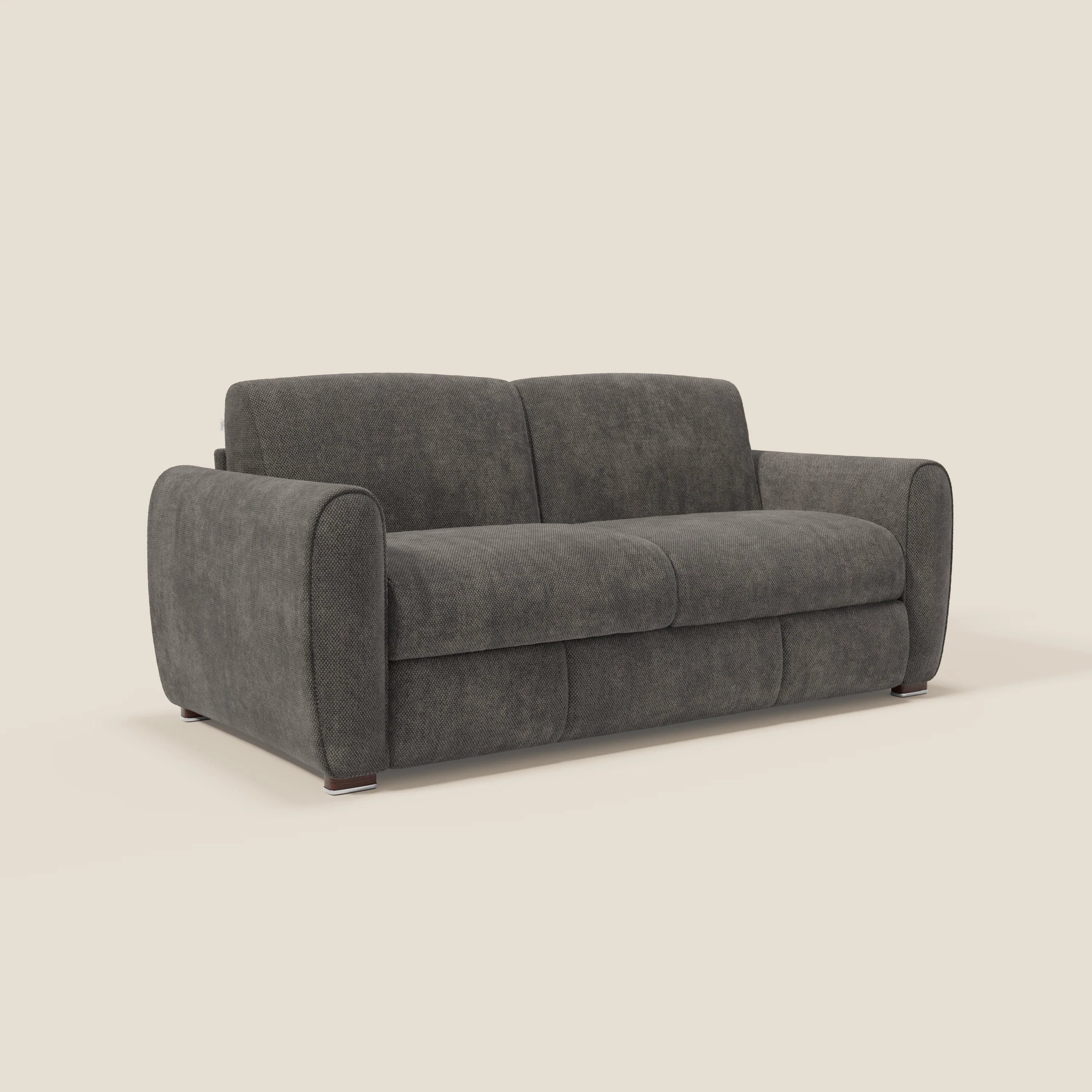 Il divano letto moderno Kaleo di Divani.Store è caratterizzato da cuscini in tessuto morbido, braccioli arrotondati e tessuto impermeabile T26 antracite. Questo divano a tre posti ha piedi bassi in legno e poggia su uno sfondo beige chiaro. Include materasso H17 cm.