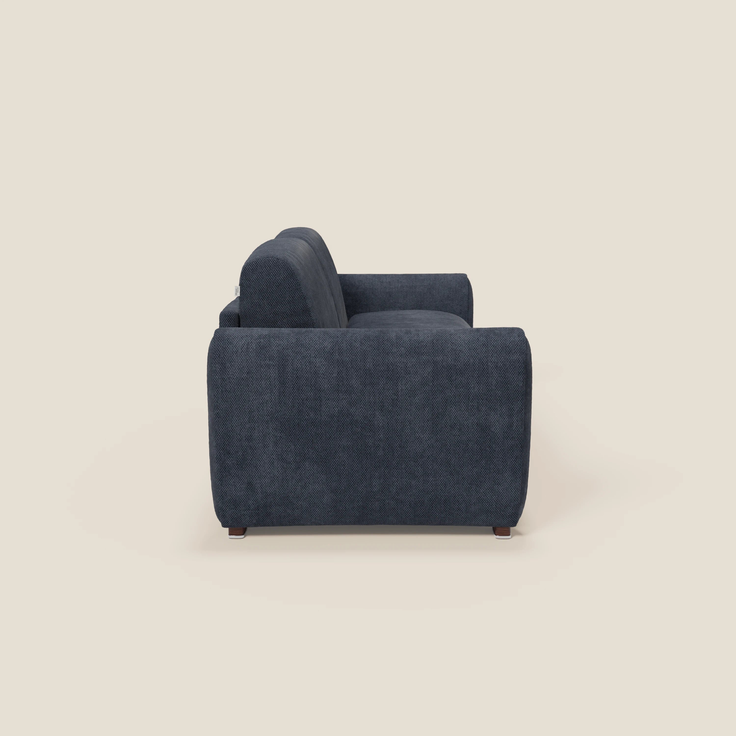 Vista laterale di Kaleo Divano letto moderno di Divani.Store, in tessuto impermeabile T26 blu navy con braccioli in tessuto, schienale imbottito e gambe corte in legno scuro, su sfondo beige chiaro.