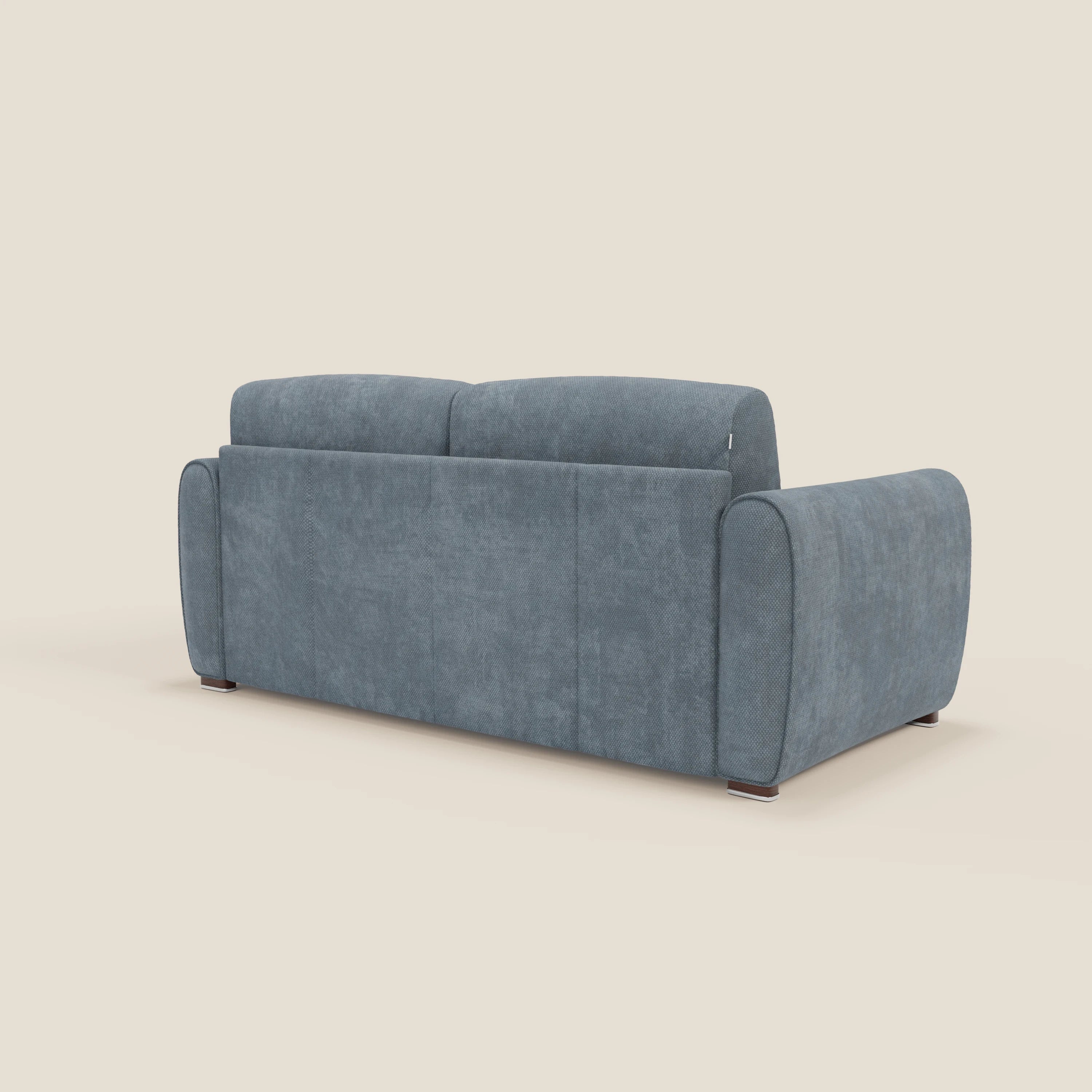 Il divano letto moderno Kaleo di Divani.Store, in tessuto impermeabile T26 carta da zucchero, è caratterizzato da braccioli arrotondati e da uno schienale alto, mostrato inclinato rispetto allo schienale su corte gambe scure su uno sfondo beige semplice.